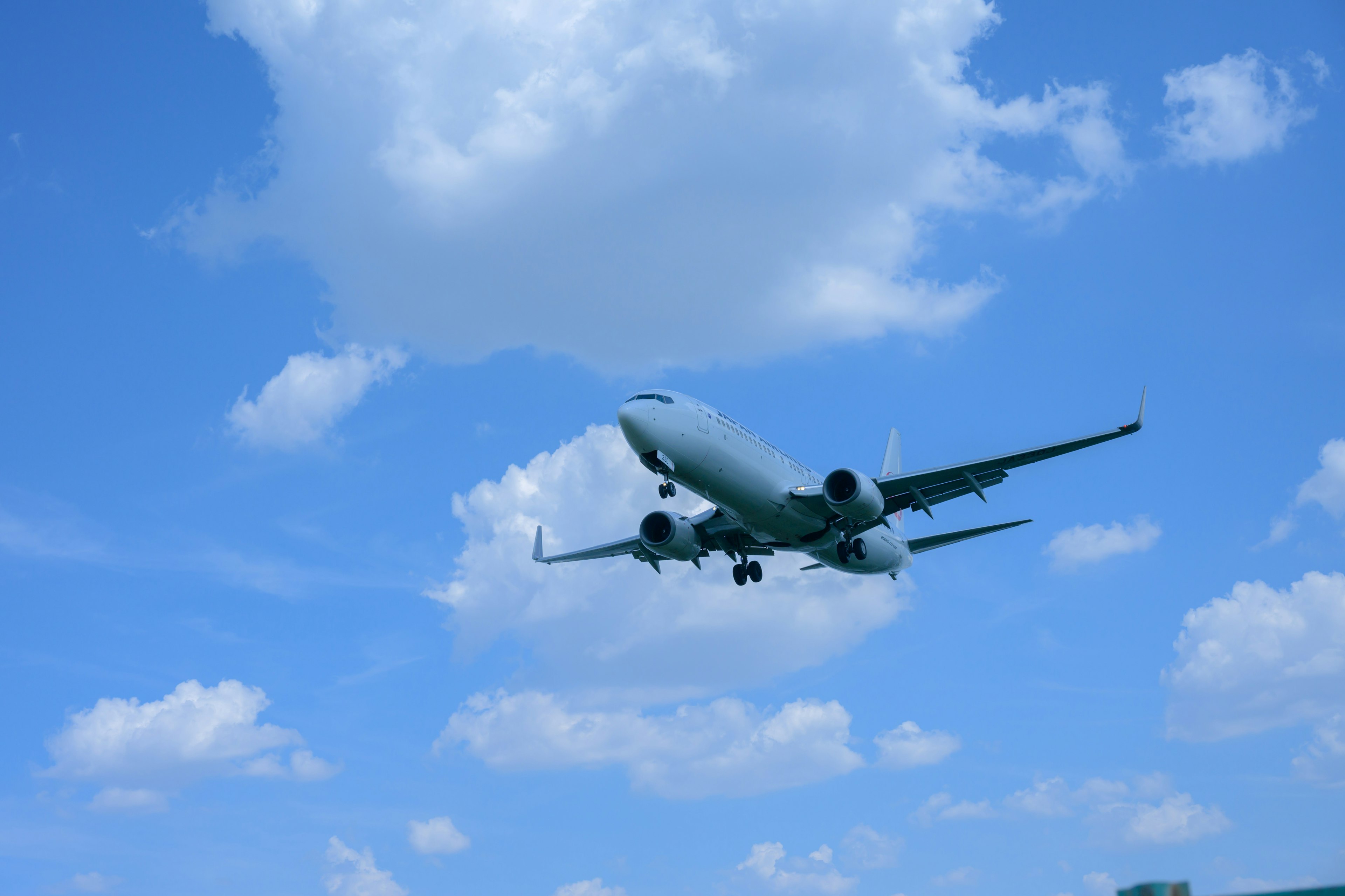 Ein Flugzeug, das vor einem blauen Himmel mit flauschigen Wolken fliegt