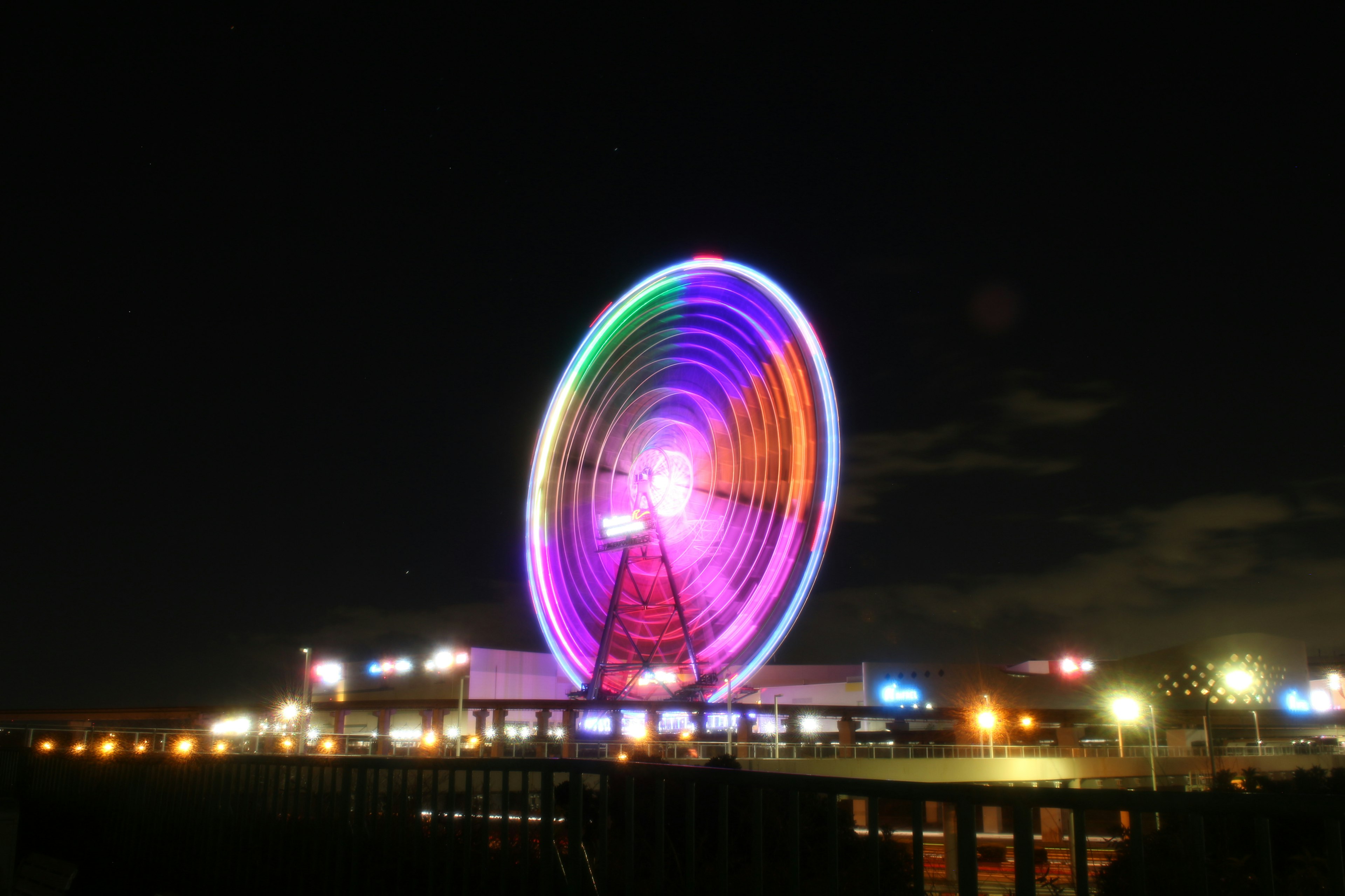 夜の観覧車がカラフルに光り輝く景色