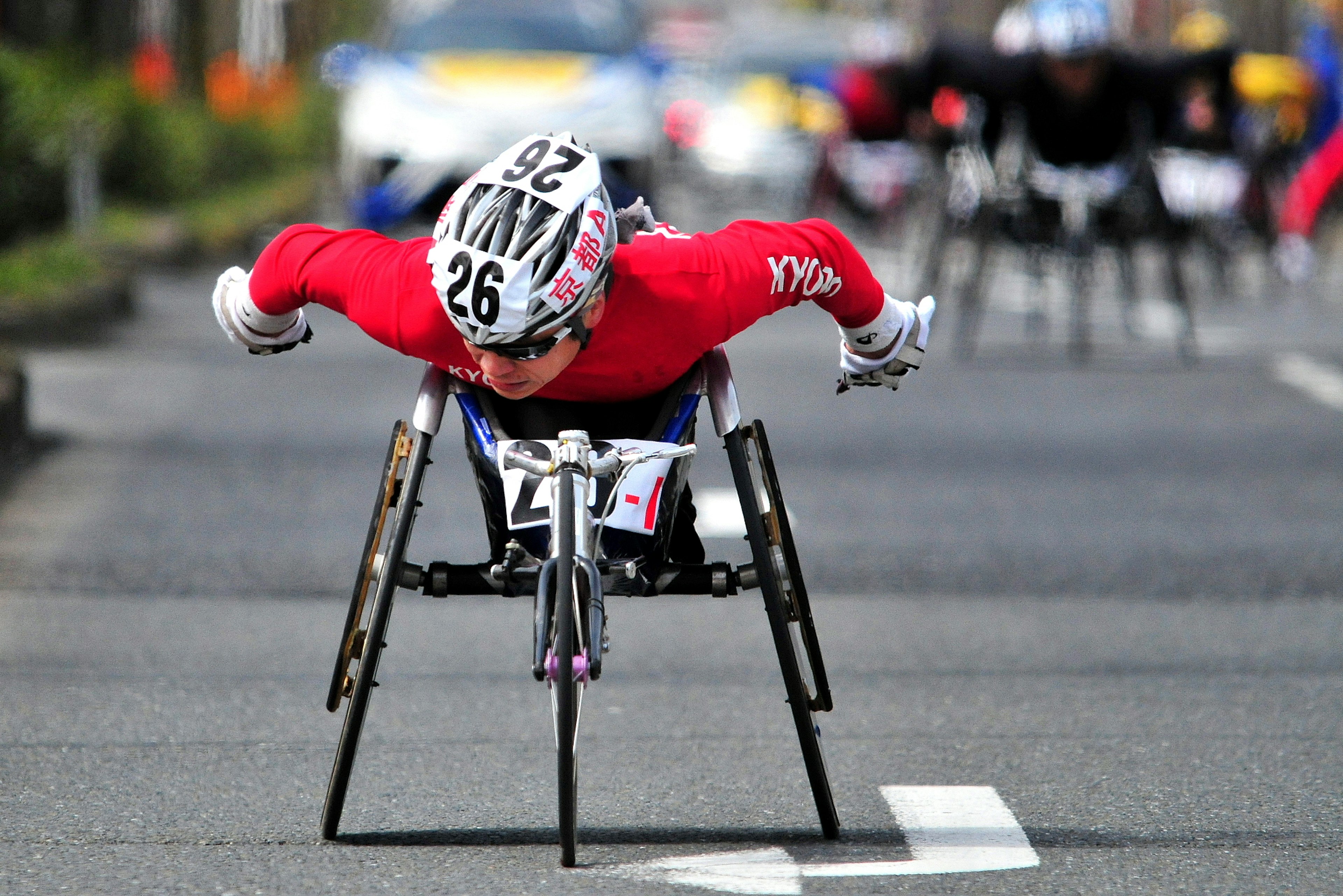 A wheelchair athlete in a red outfit racing towards the finish line