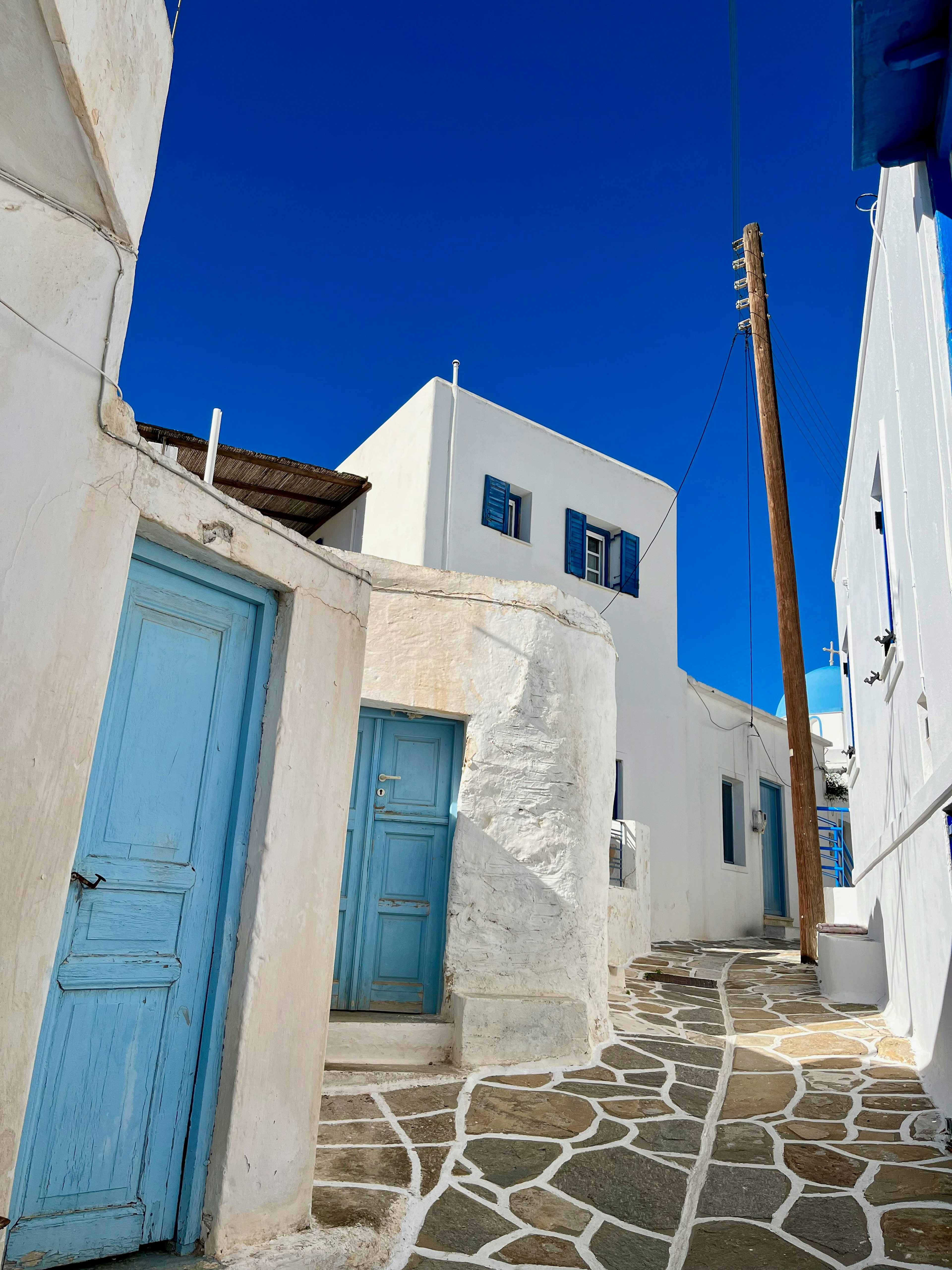 A scenic view of white buildings with blue doors and a stone pathway