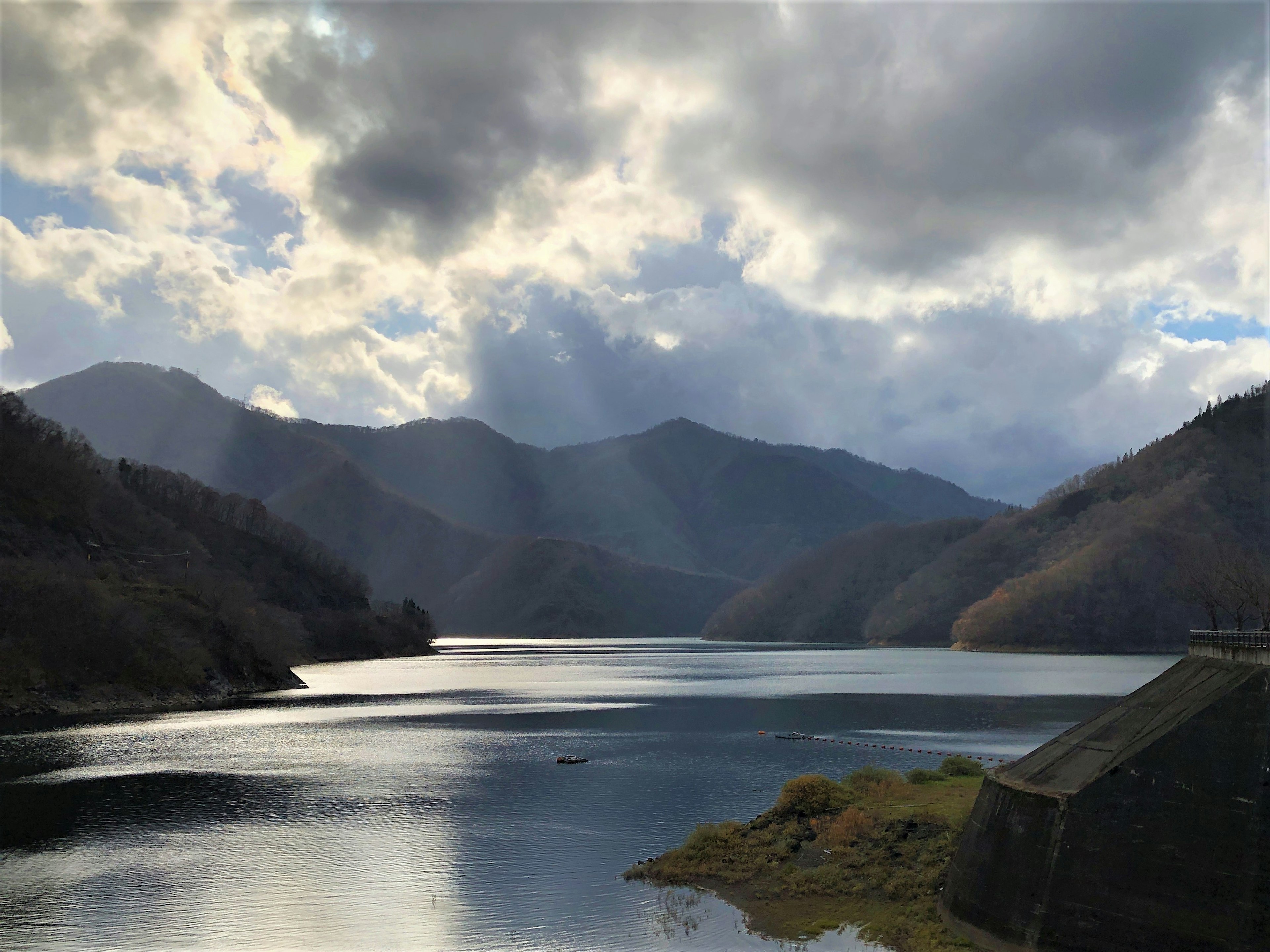 山々と湖の美しい風景に、雲の間から光が差し込む