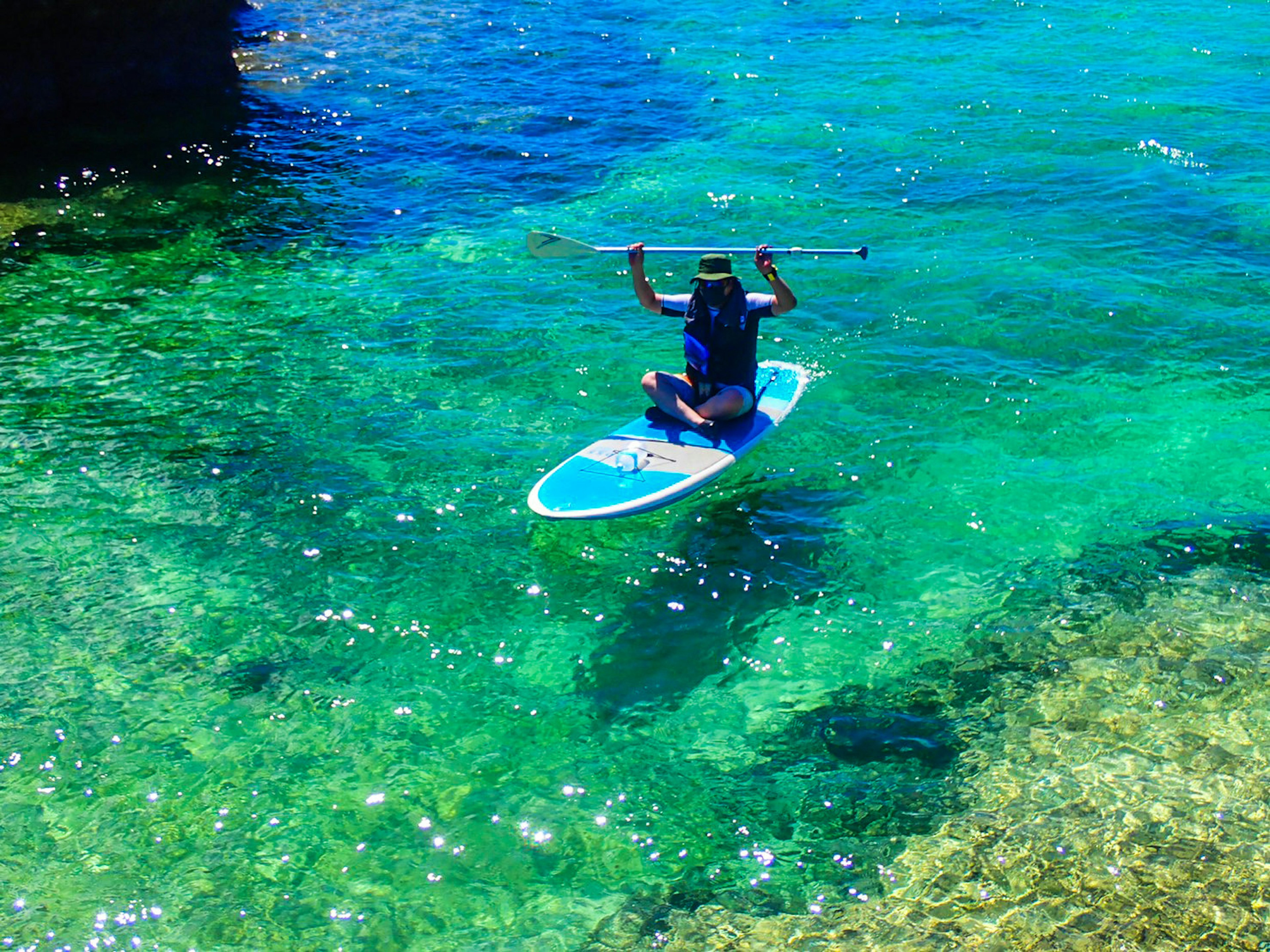 Personne pratiquant le paddle sur une eau turquoise claire