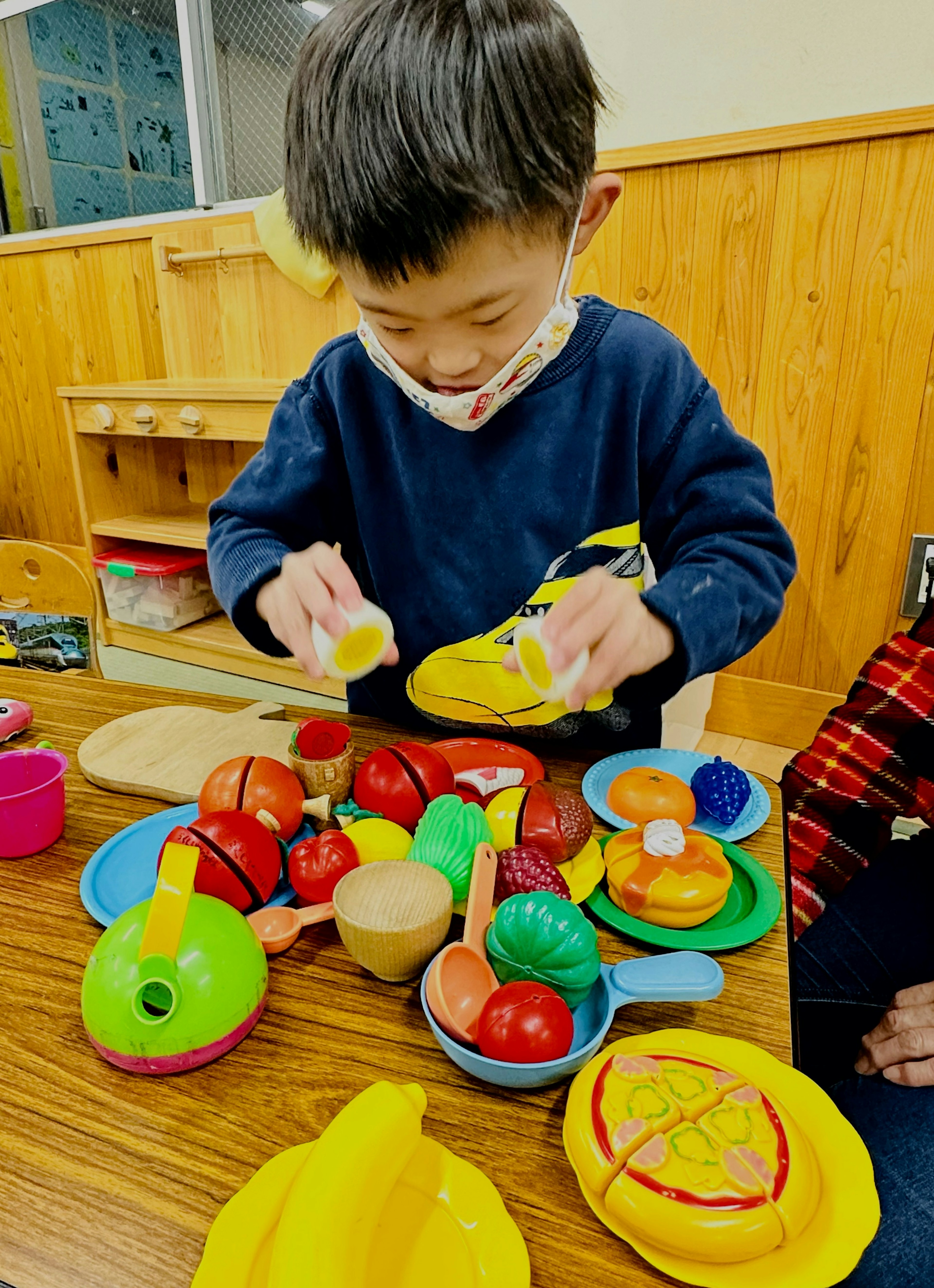 어린이가 테이블 위에서 장난감 과일로 놀고 있는 모습