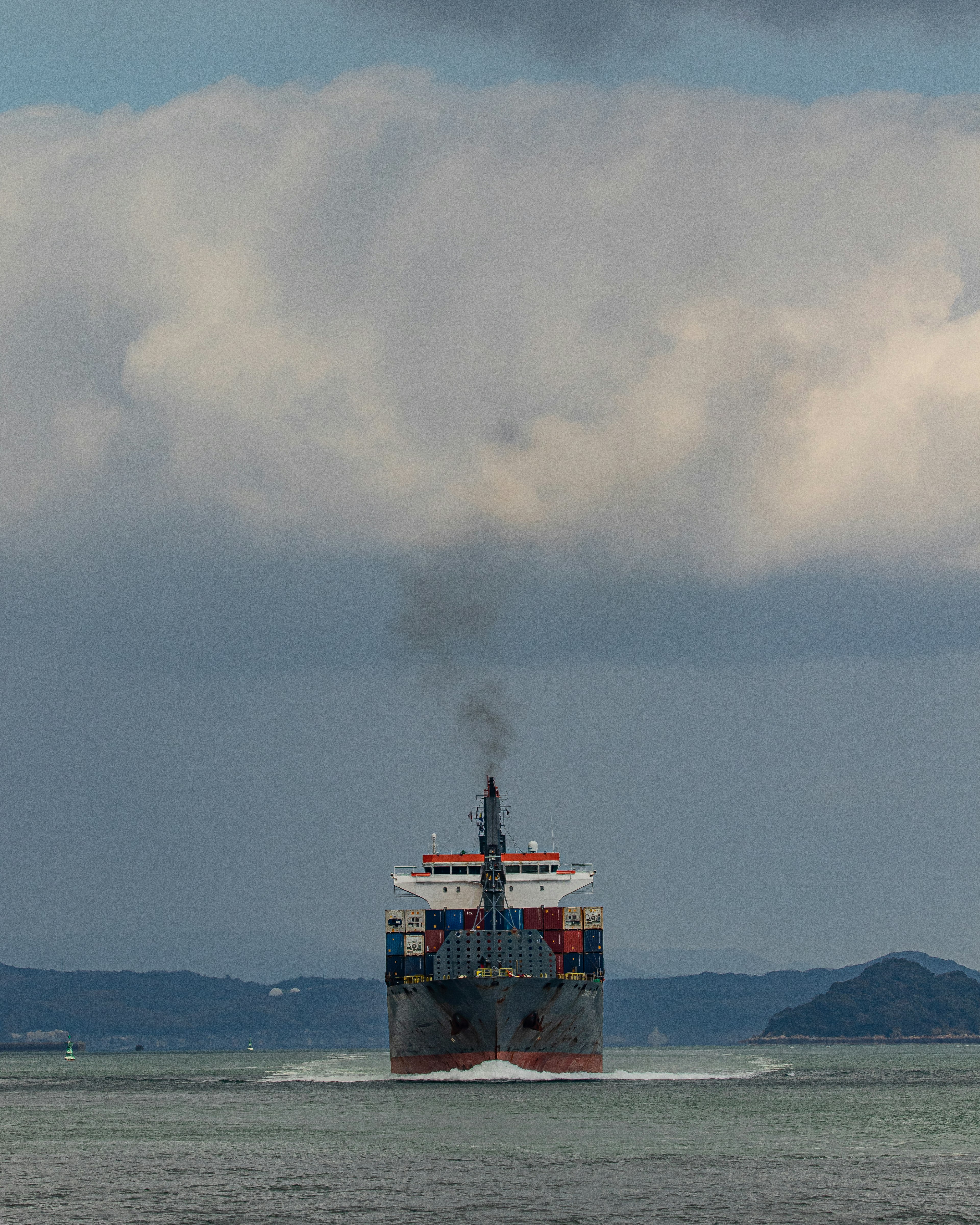 Containerschiff, das Rauch ausstößt und auf dem Meer segelt