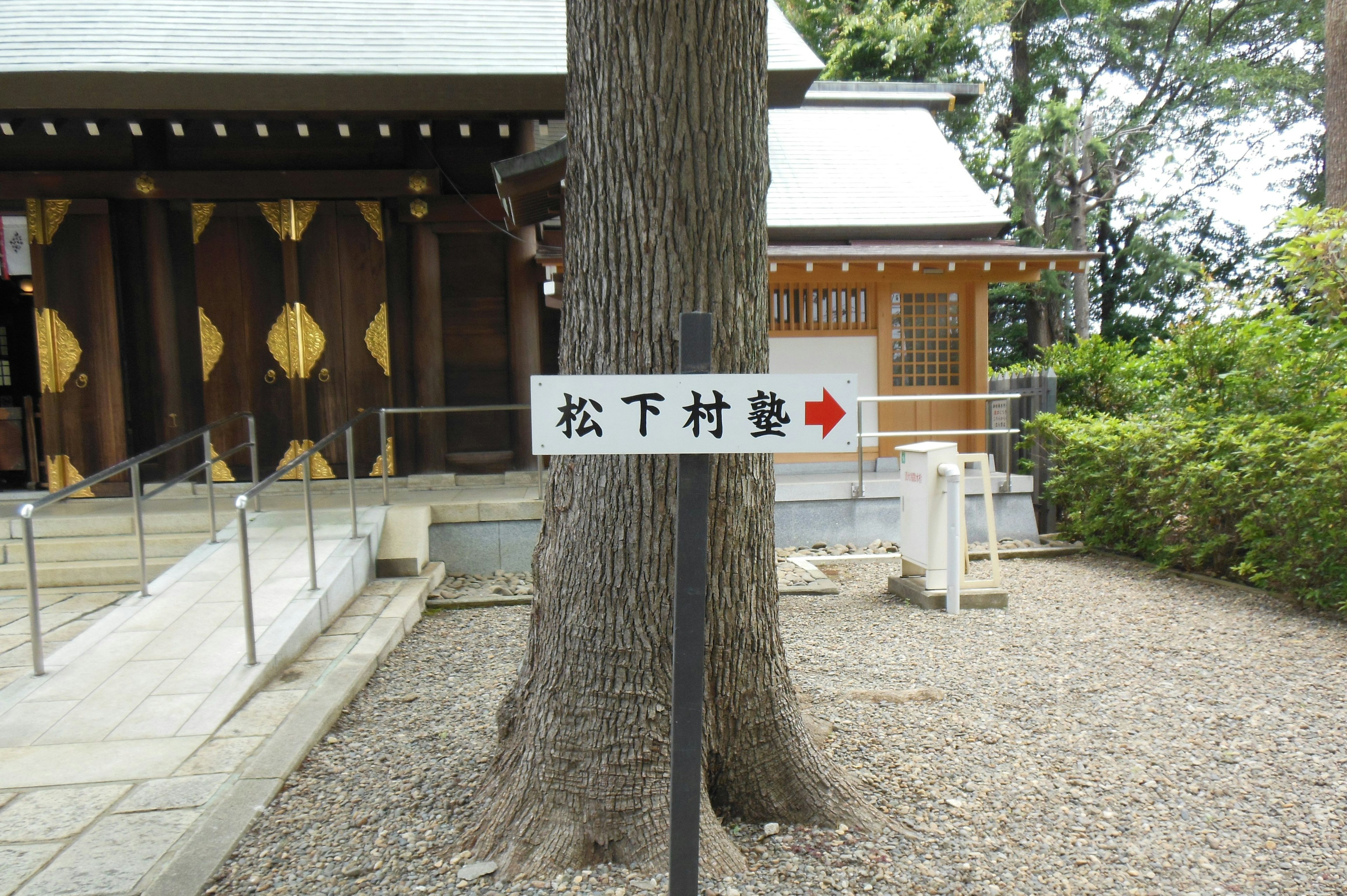 Sign for Matsushita Village School with traditional architecture in the background