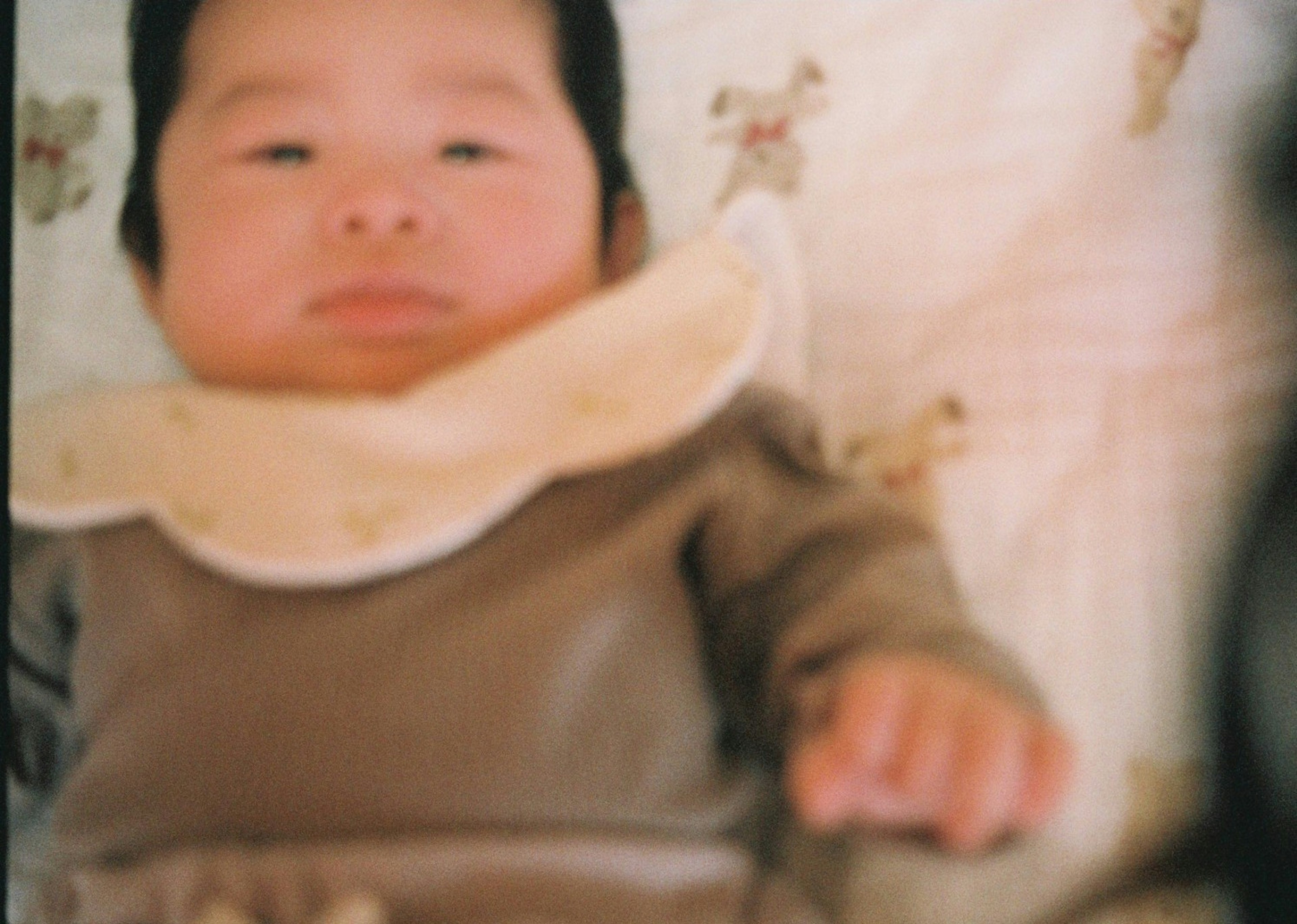 A baby lying on a bed wearing a beige-collared outfit