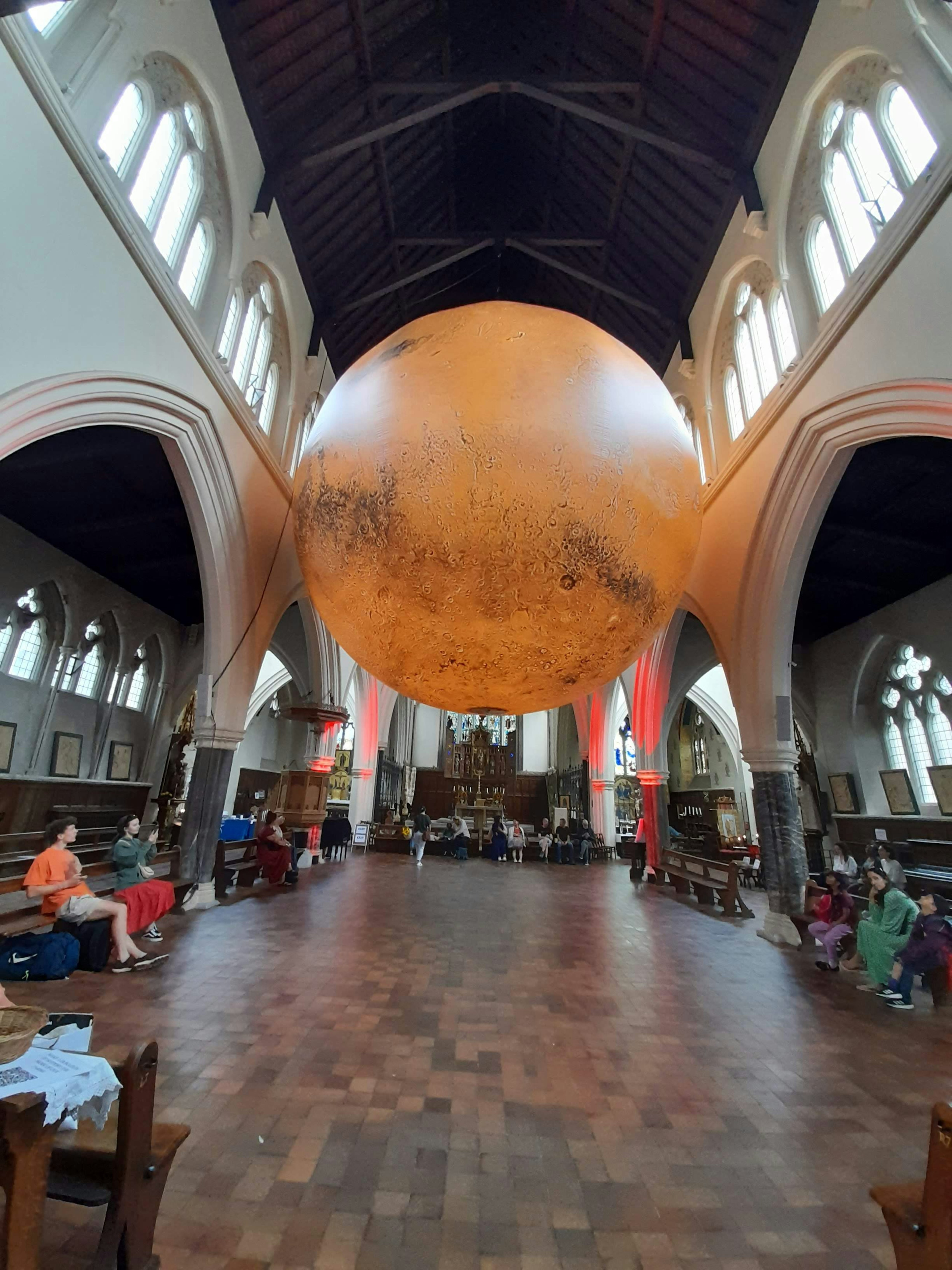 Grande mappa del mondo sospesa all'interno di una chiesa con sedie in legno