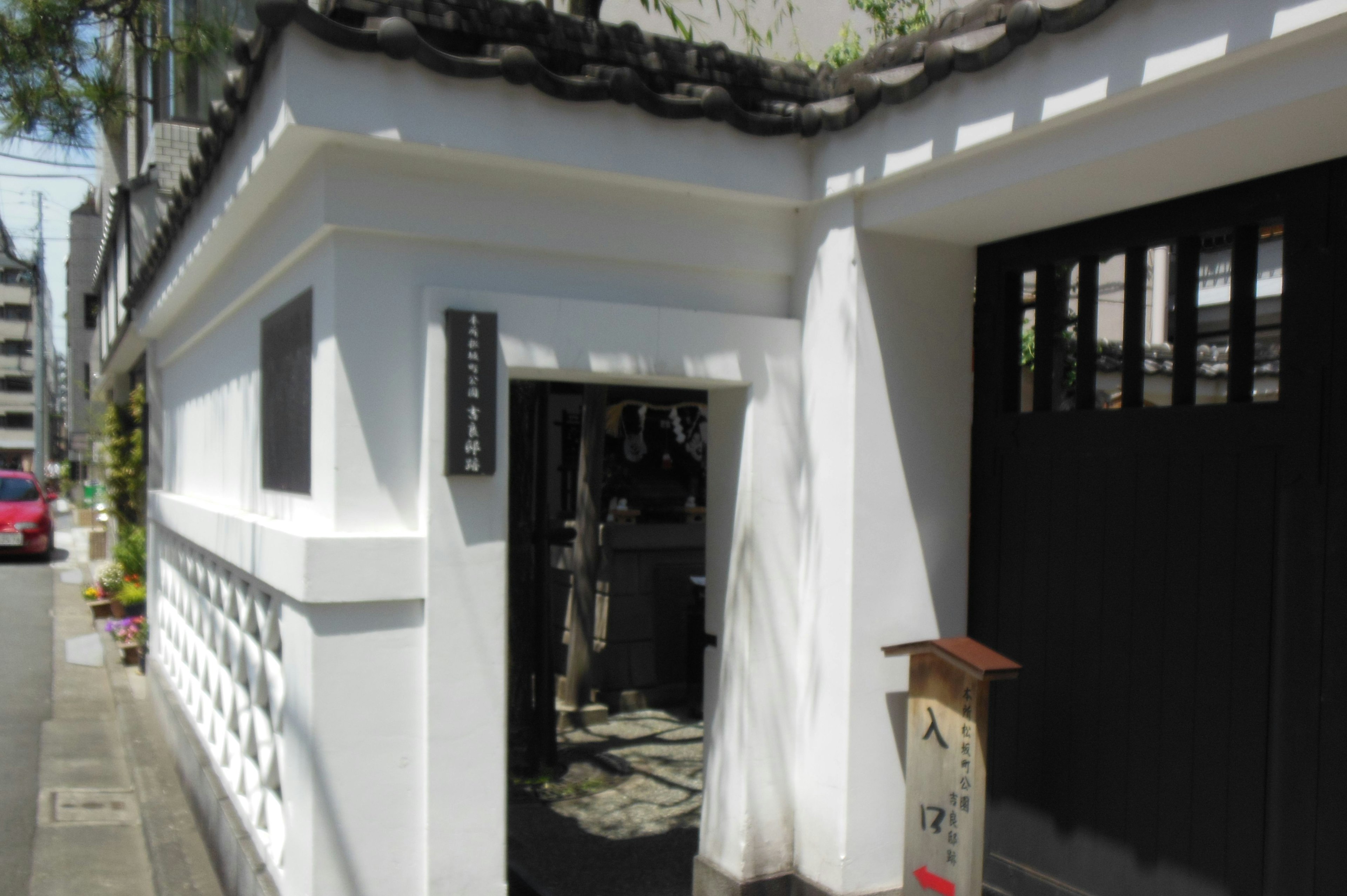 Entrée d'un bâtiment japonais traditionnel avec des murs blancs et une porte noire