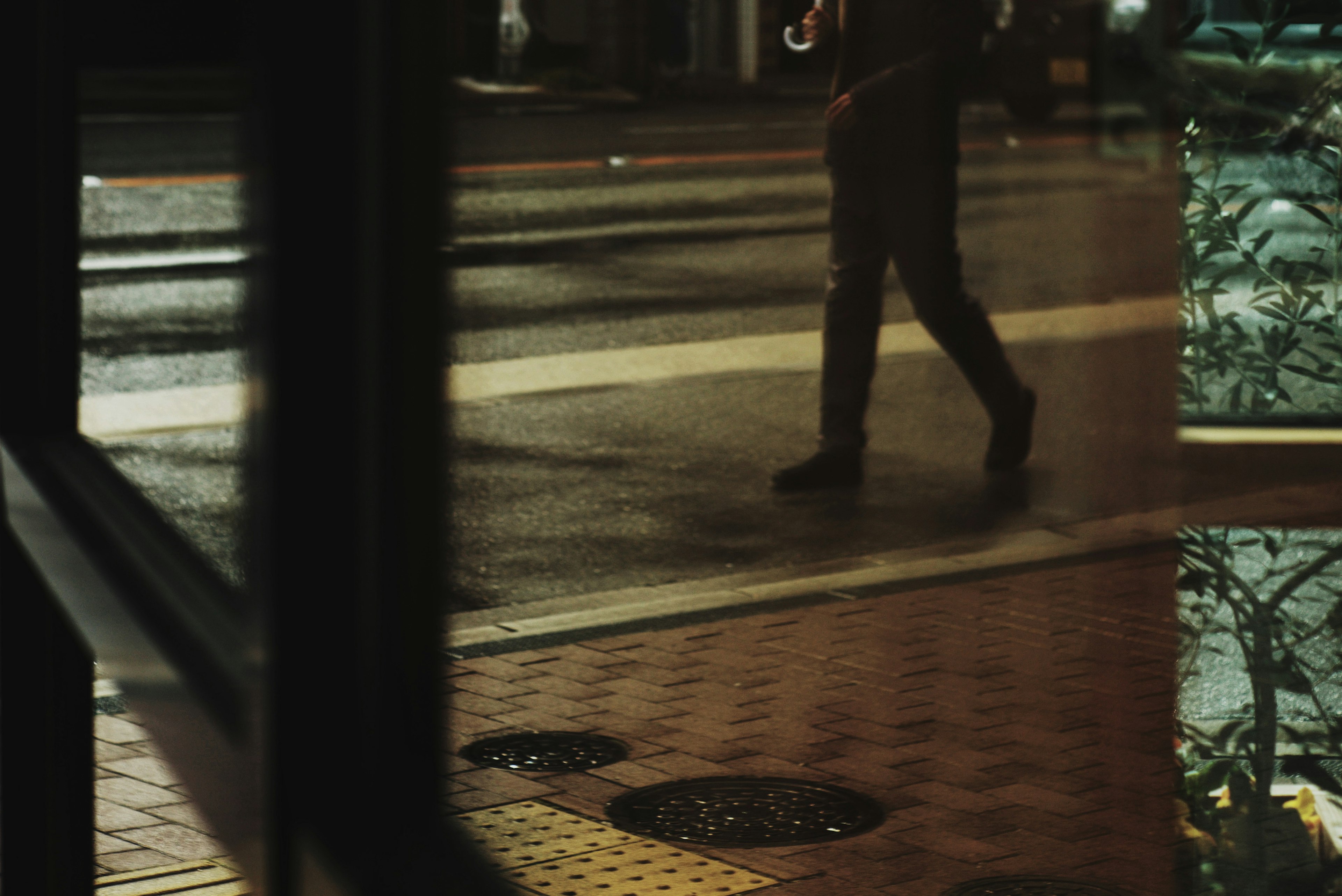 Silhouette of a person walking in the rain with reflections on the pavement