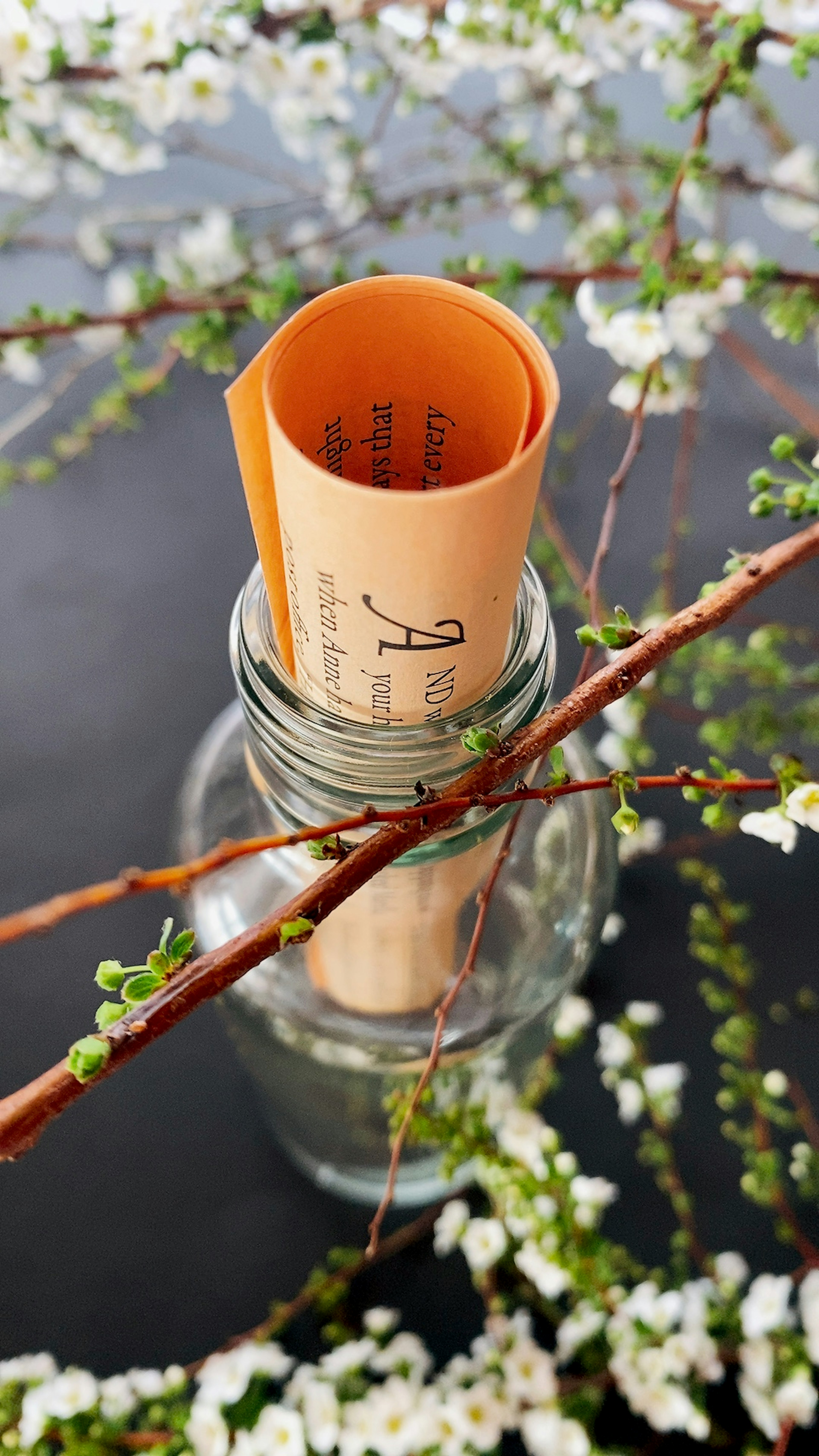 Scroll in a glass jar surrounded by floral branches