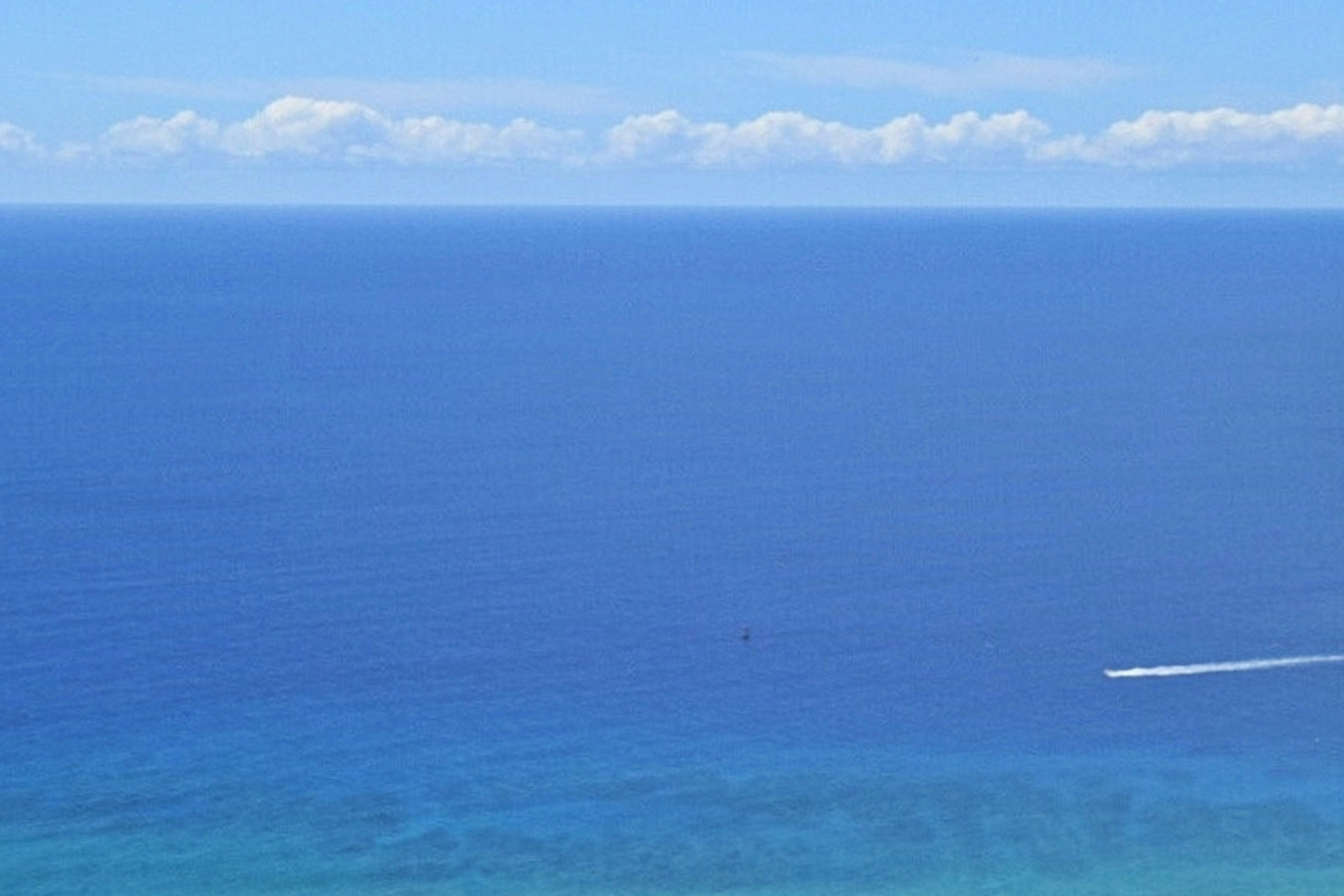 Weites blaues Meer und Himmel mit weißen Wolken Boot fährt