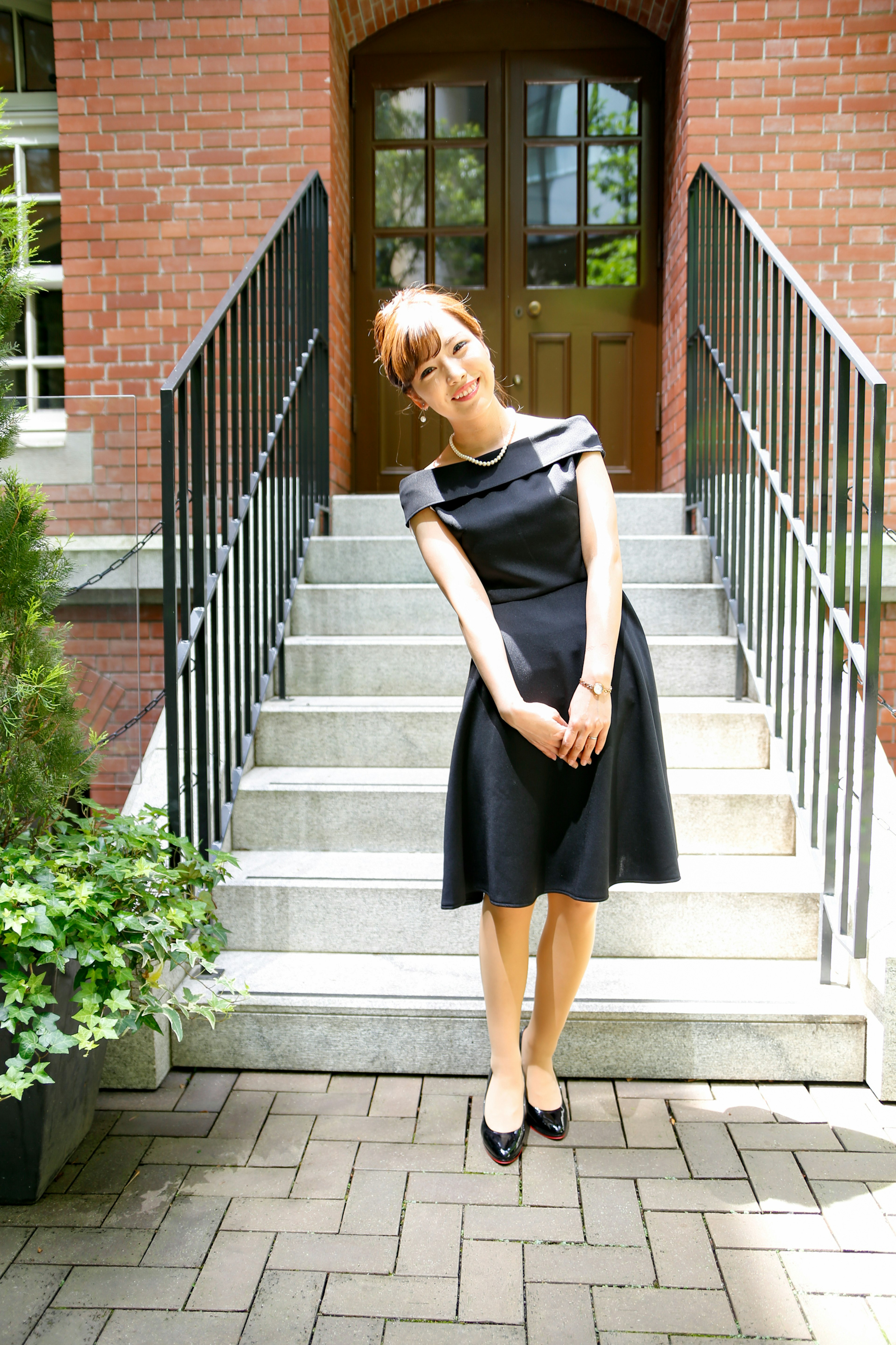 Una mujer con un vestido negro posando en una escalera