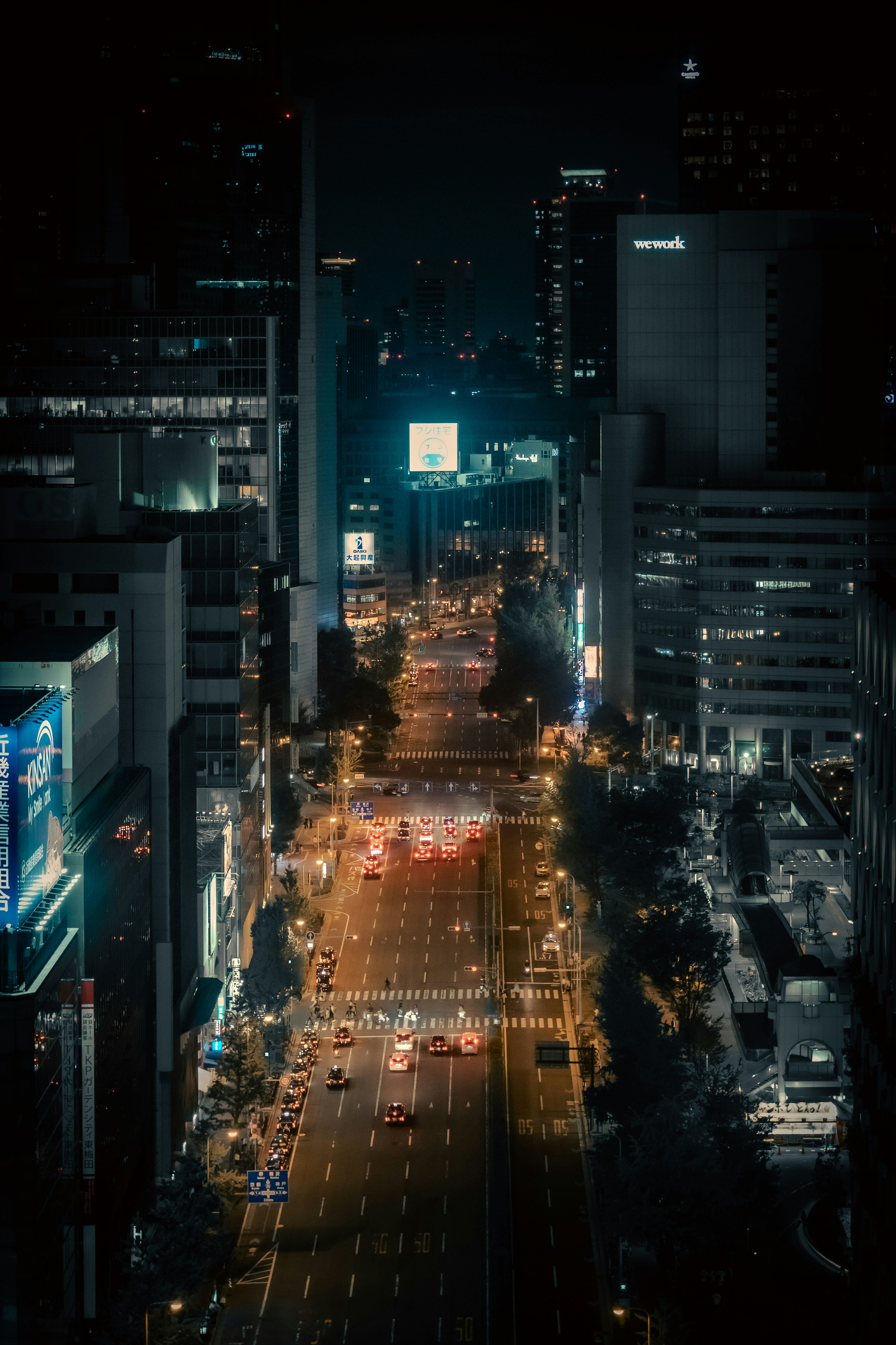 Nighttime cityscape with illuminated streets, building lights, and traffic flow