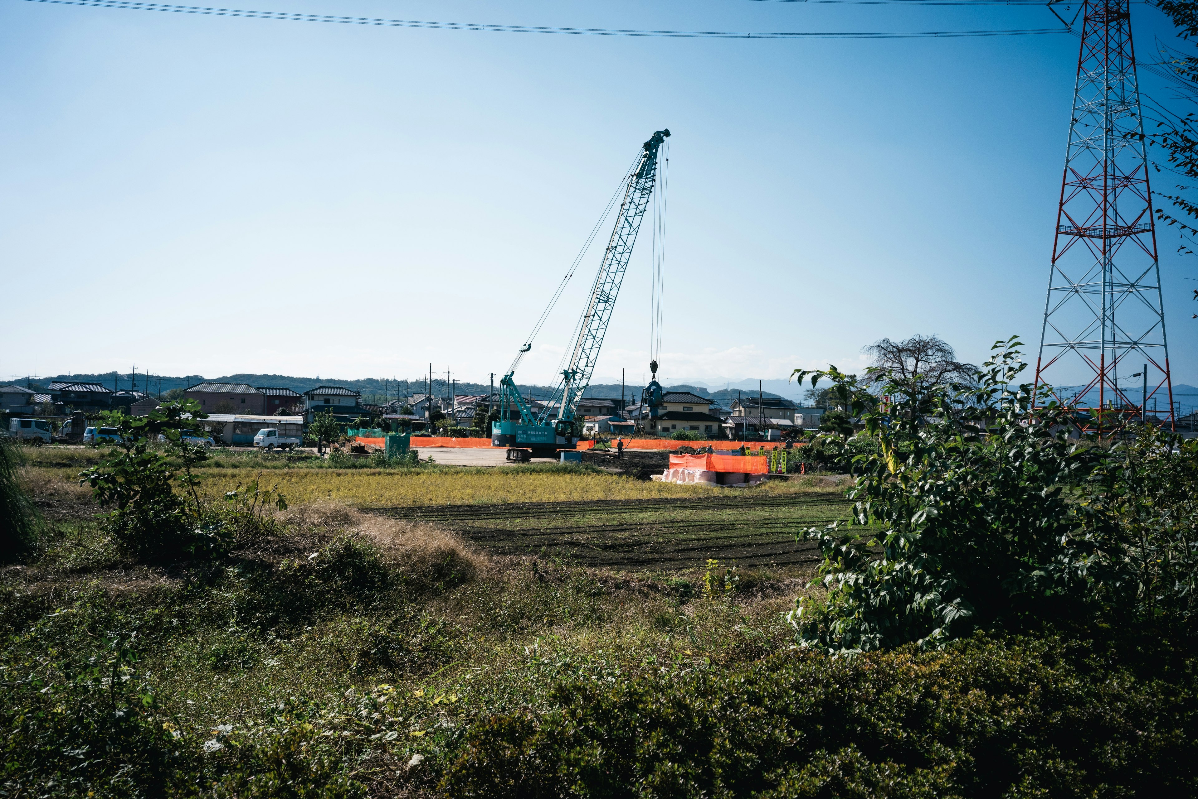 Large crane near farmland under a clear blue sky