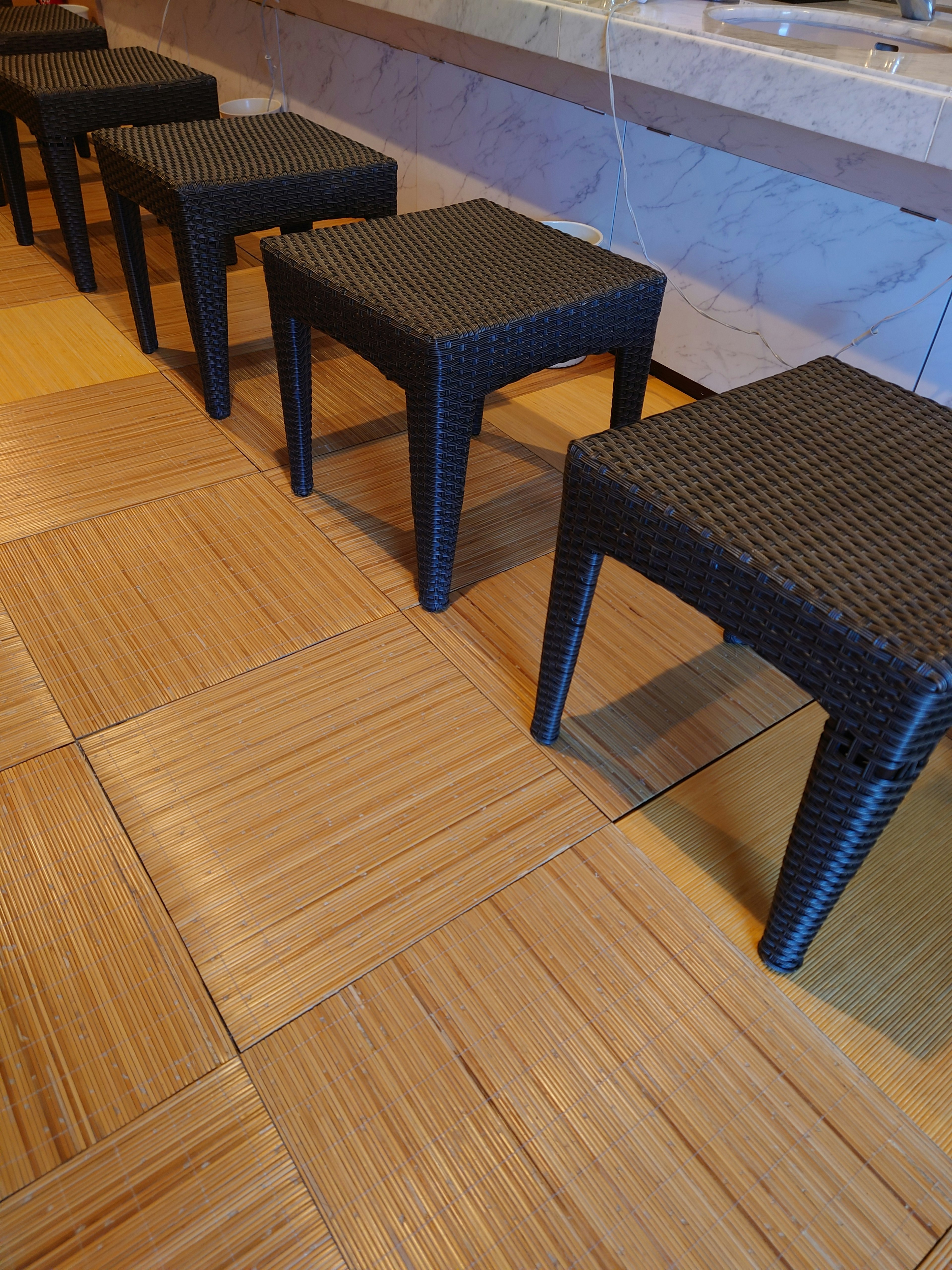 Row of black plastic stools on a wooden patterned floor