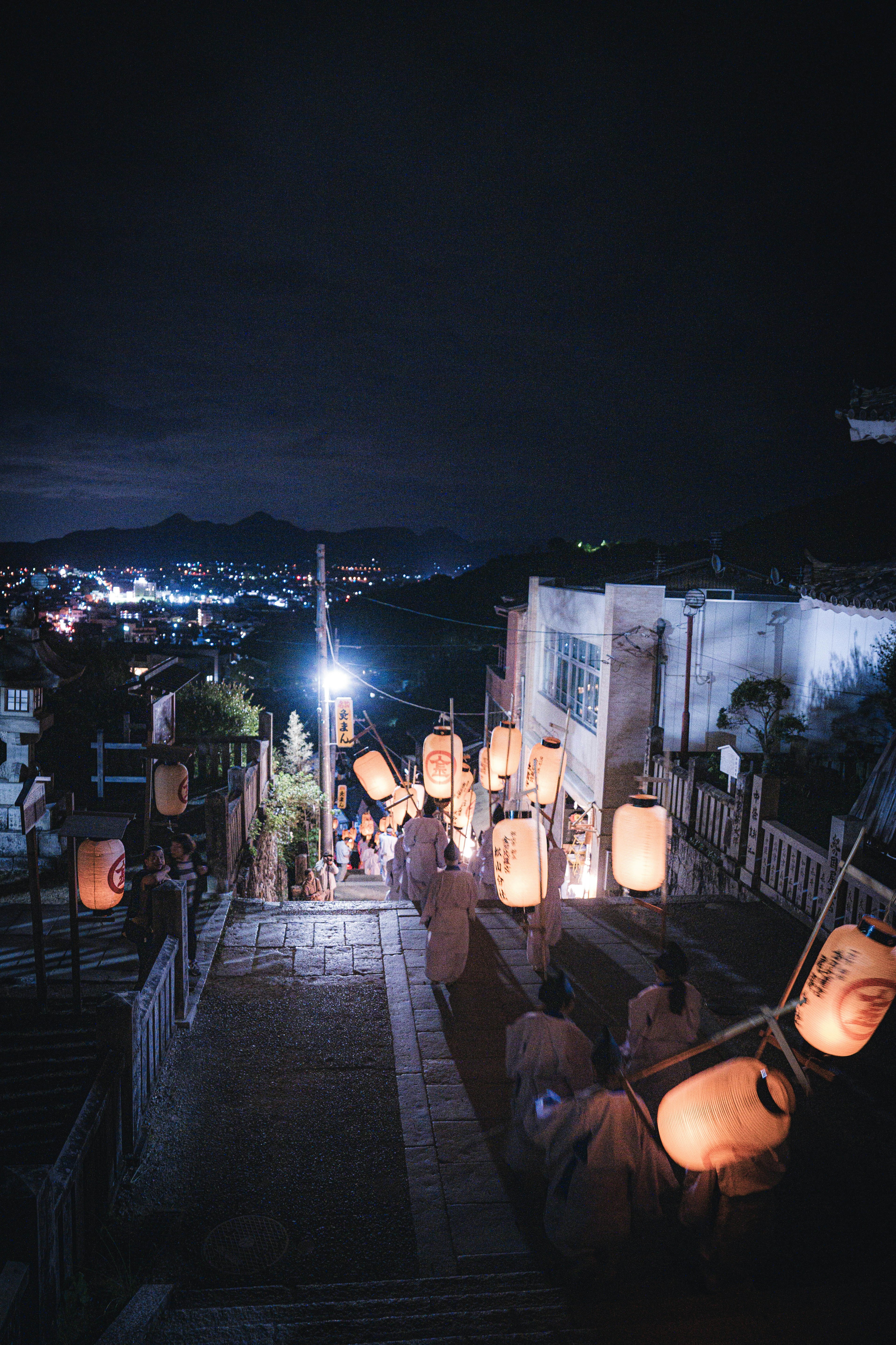 Des gens descendant des escaliers illuminés la nuit avec des lanternes