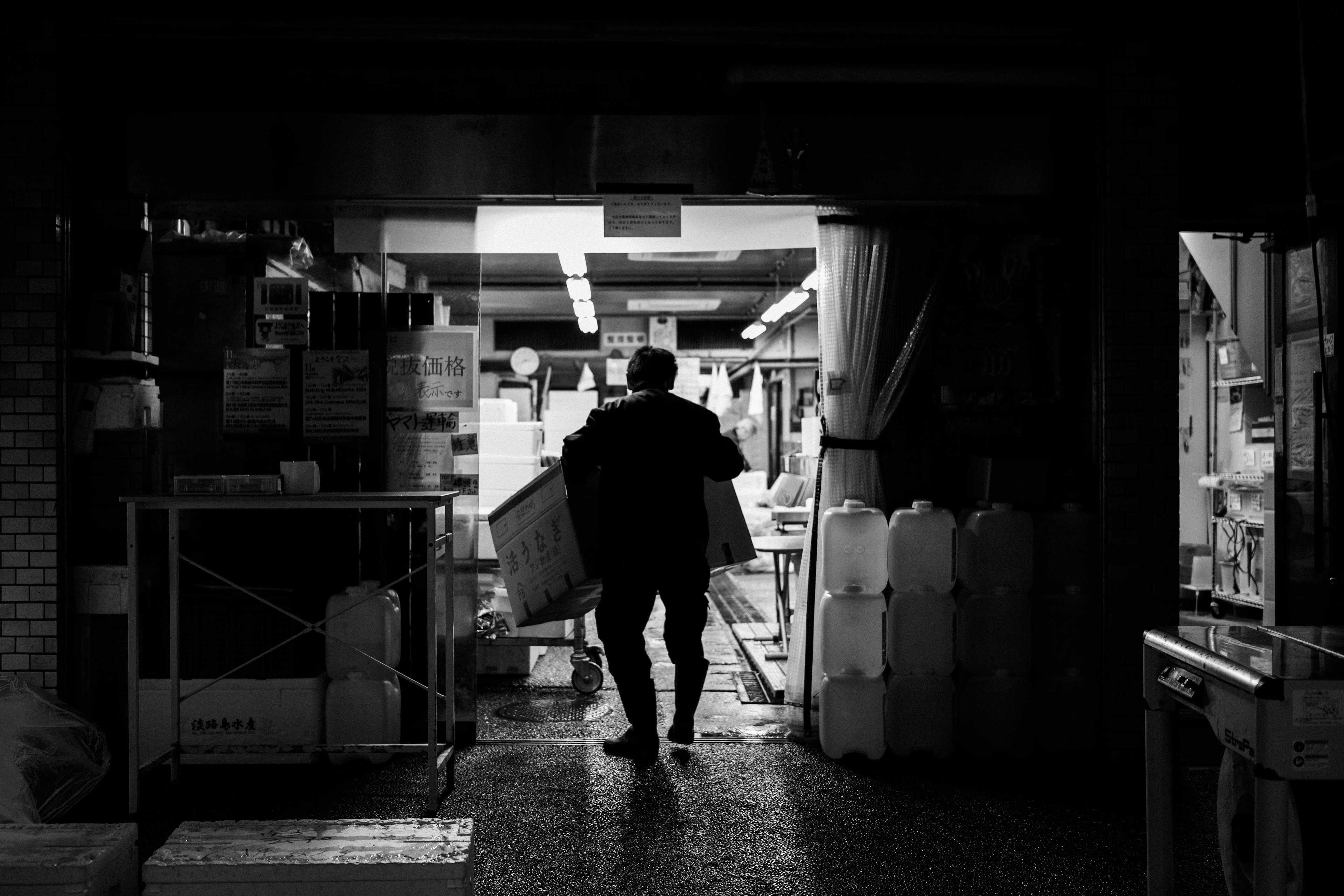 Un homme portant une boîte marchant dans un couloir sombre