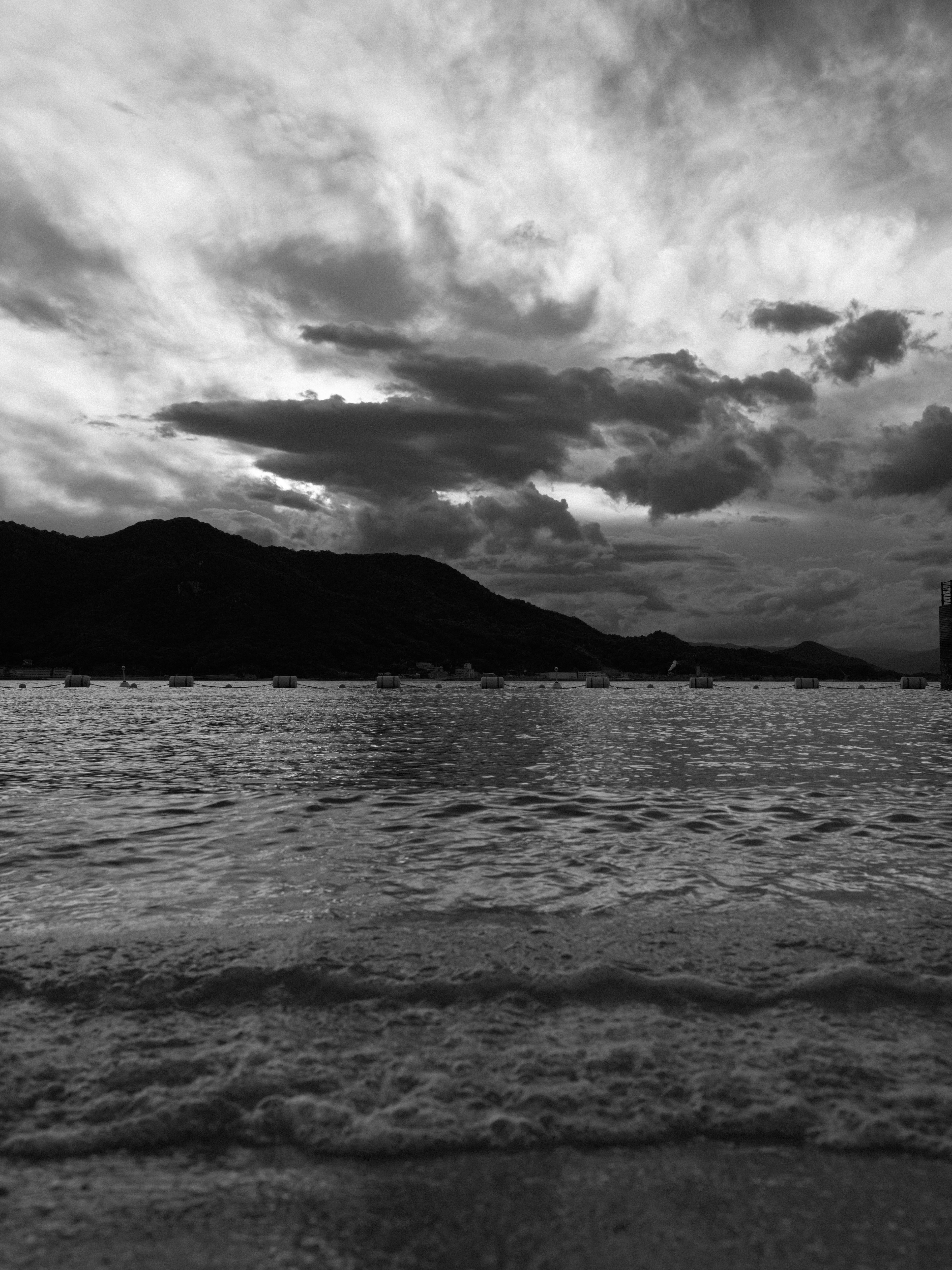 Paisaje marítimo con montañas contraste en blanco y negro cielo nublado