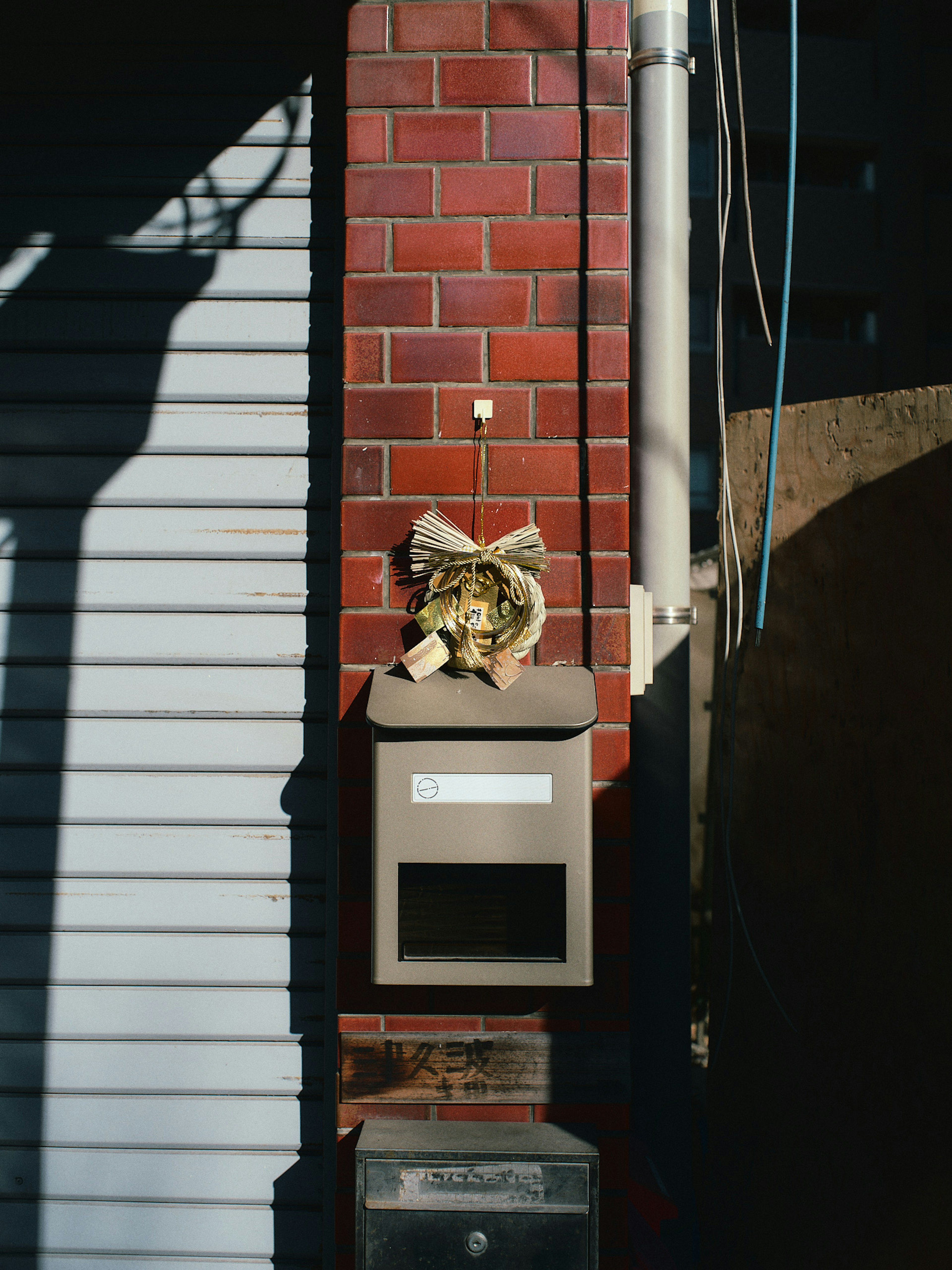 Decorative object placed on top of a mailbox attached to a red brick wall