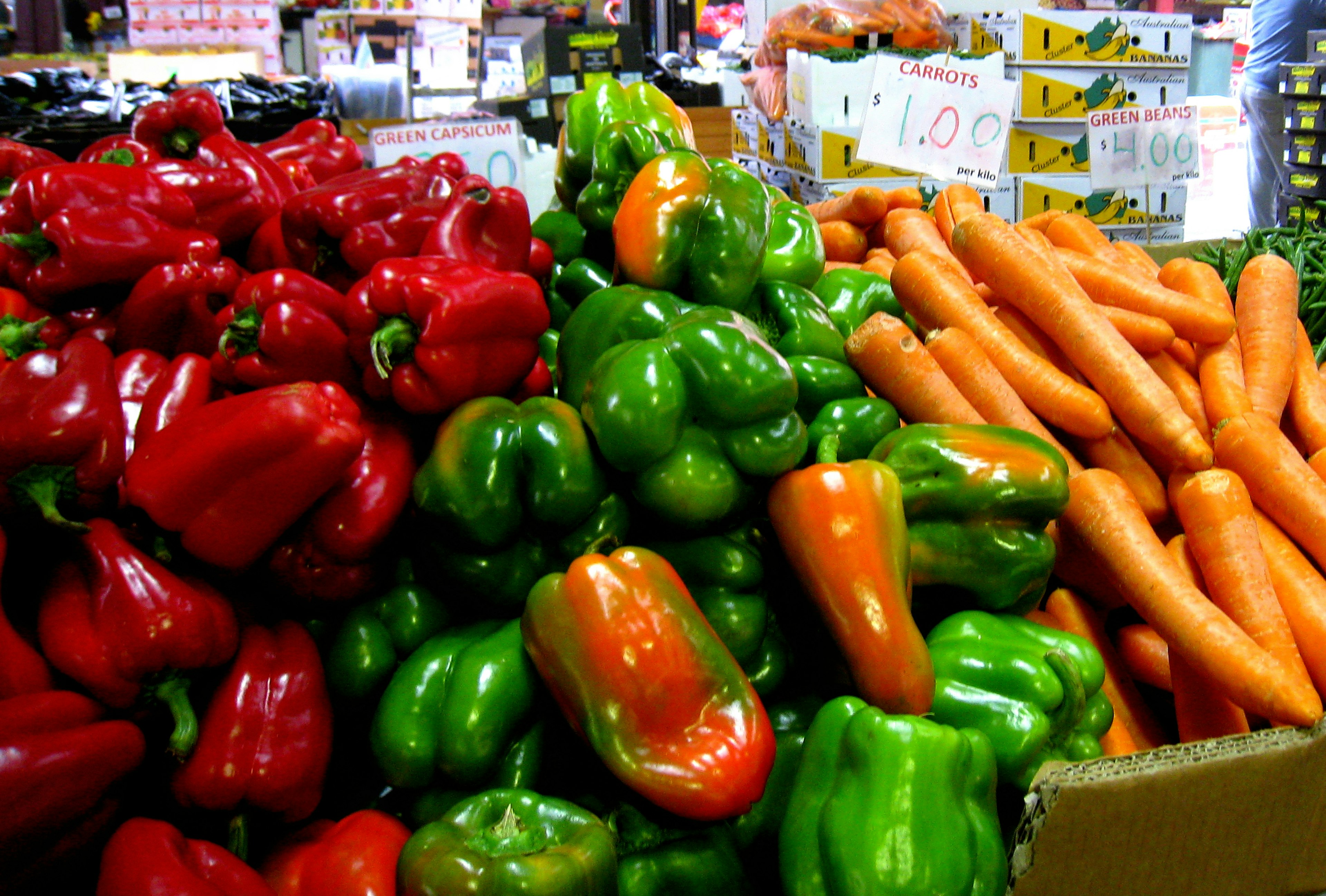 Colorful bell peppers and carrots stacked in a market setting