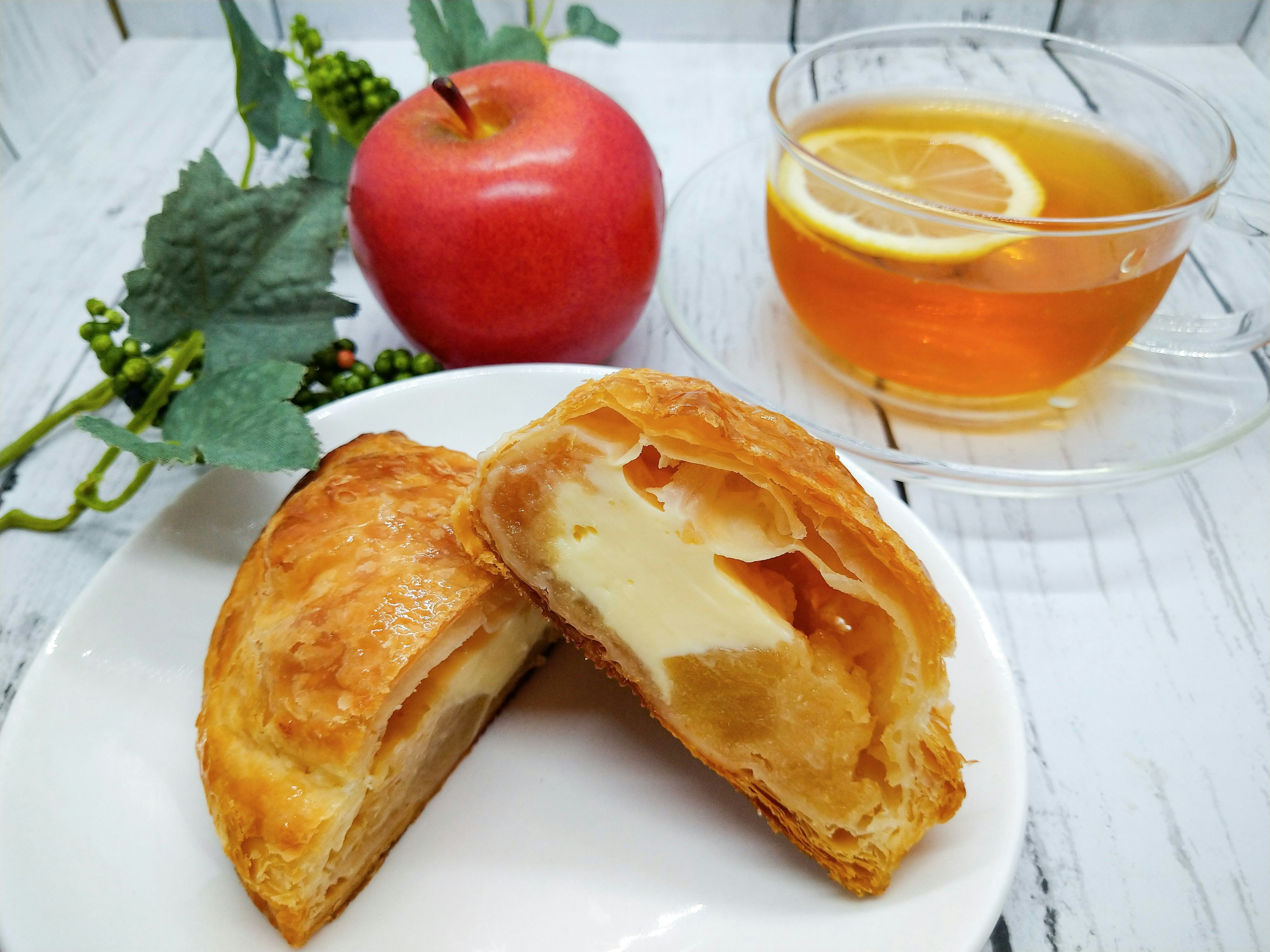 Tarte aux pommes fraîchement cuite avec une tasse de thé La tarte a une croûte feuilletée remplie de garniture de pomme sucrée Une pomme rouge et des tranches de citron sont incluses