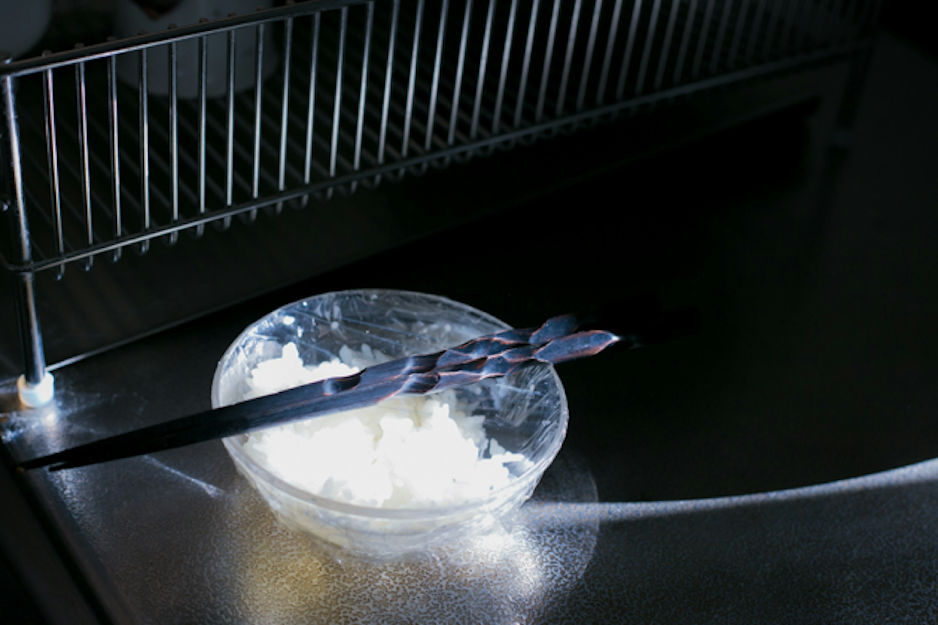 Image of a clear bowl with white cream and a black spoon