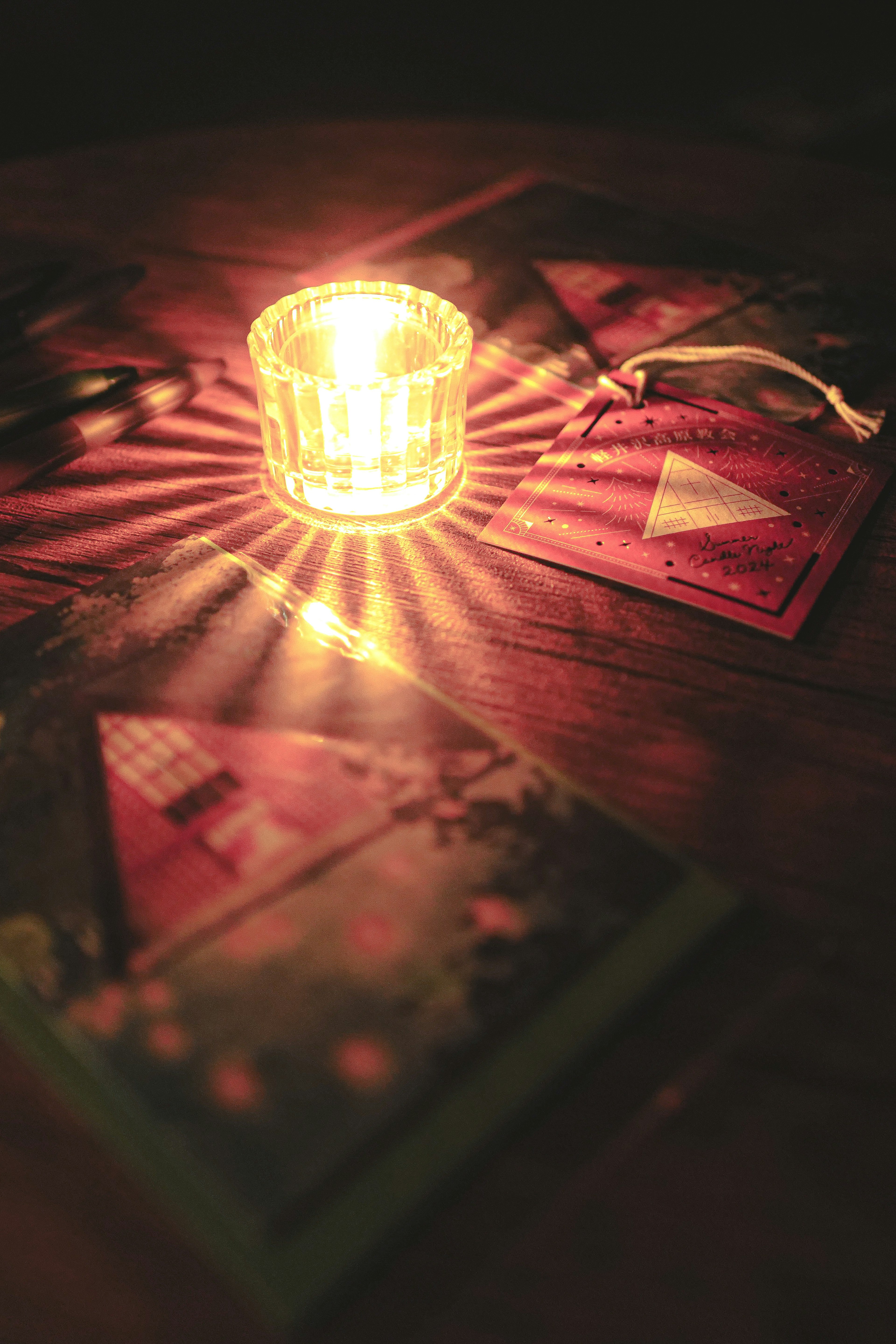 Cartes colorées disposées autour d'une bougie lumineuse sur une table en bois sombre