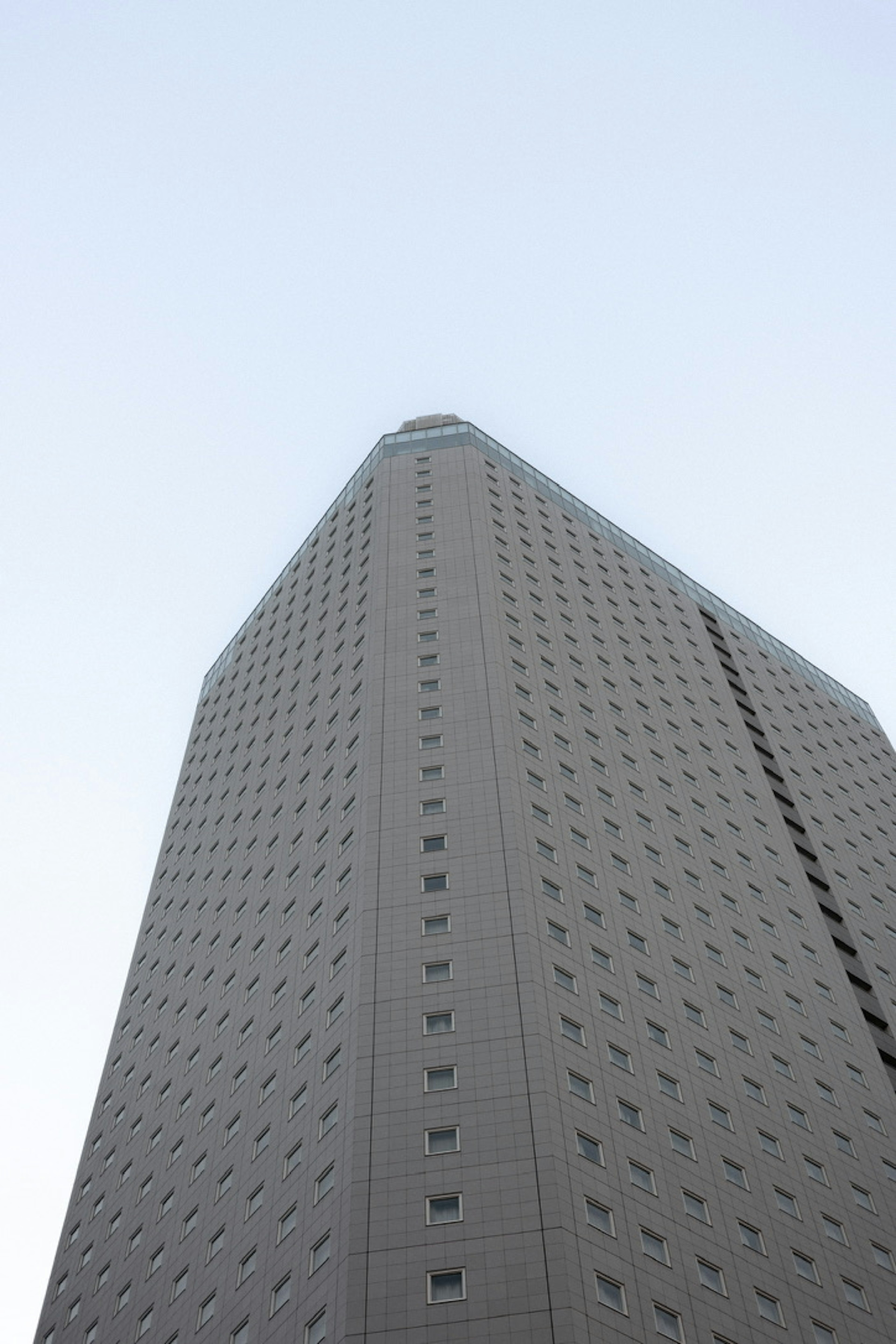 View looking up at a tall building showcasing a smooth facade and evenly spaced windows