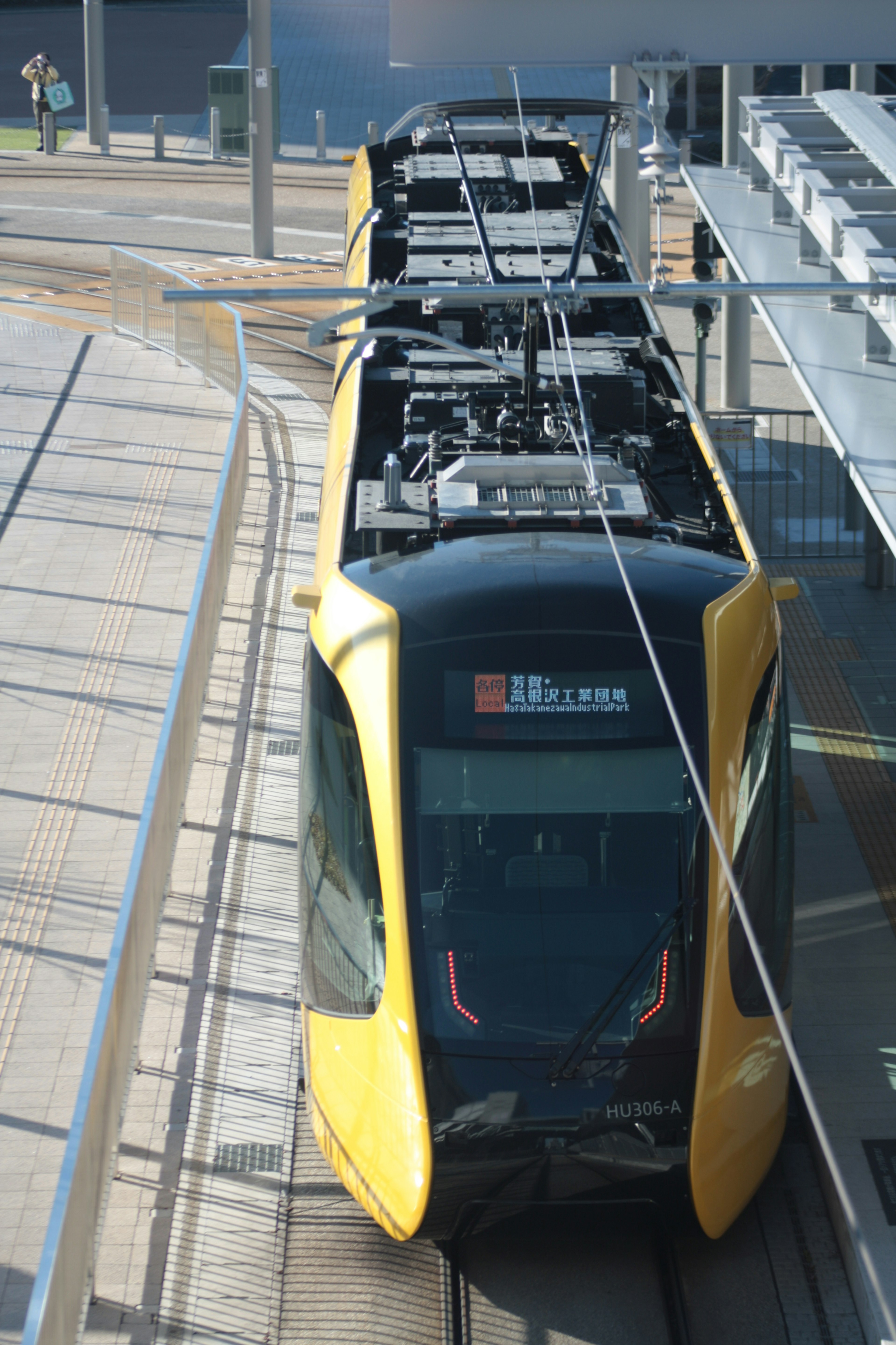 Tram modern berwarna kuning dan hitam diparkir di rel