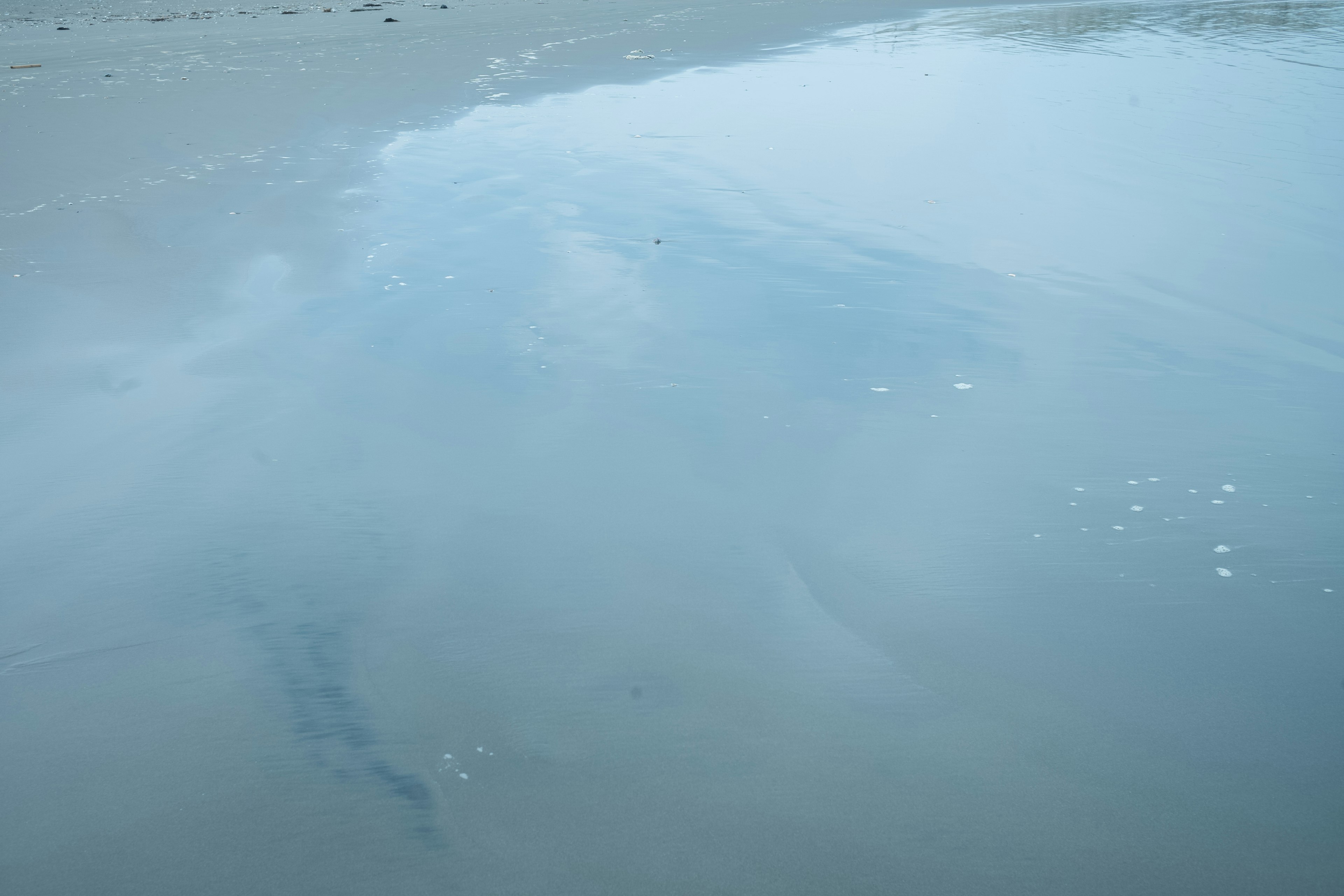 水面に映る空の青い色と波紋のある静かな海の風景