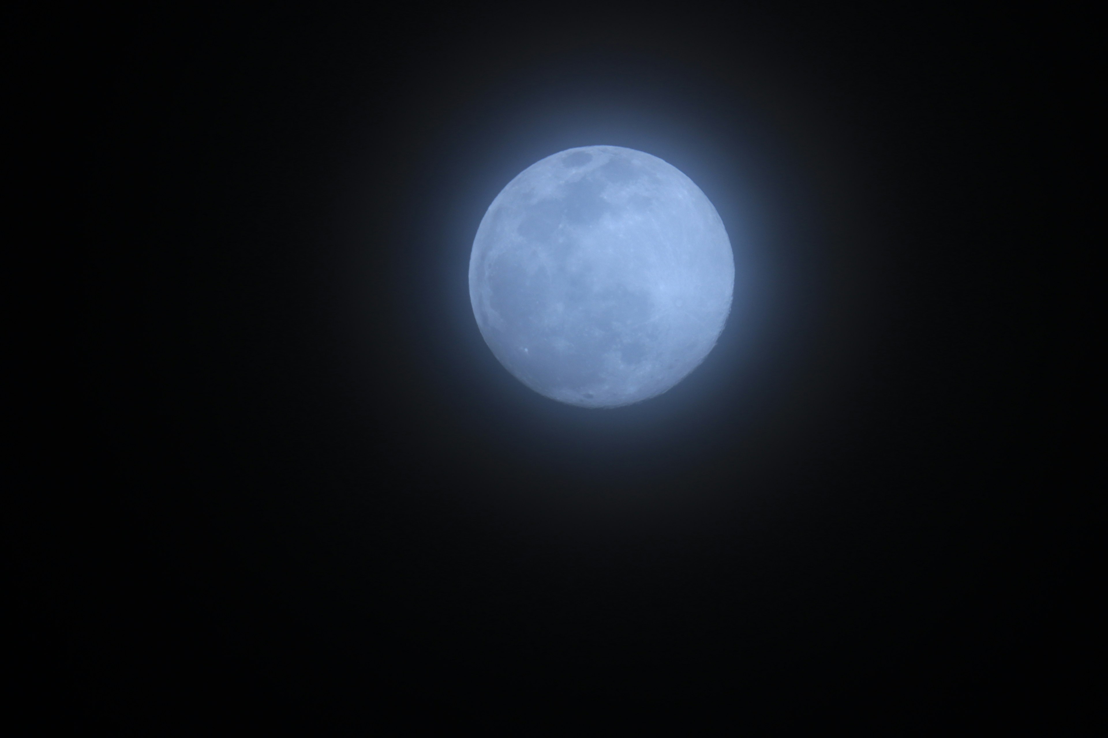 A blue moon floating in a dark sky