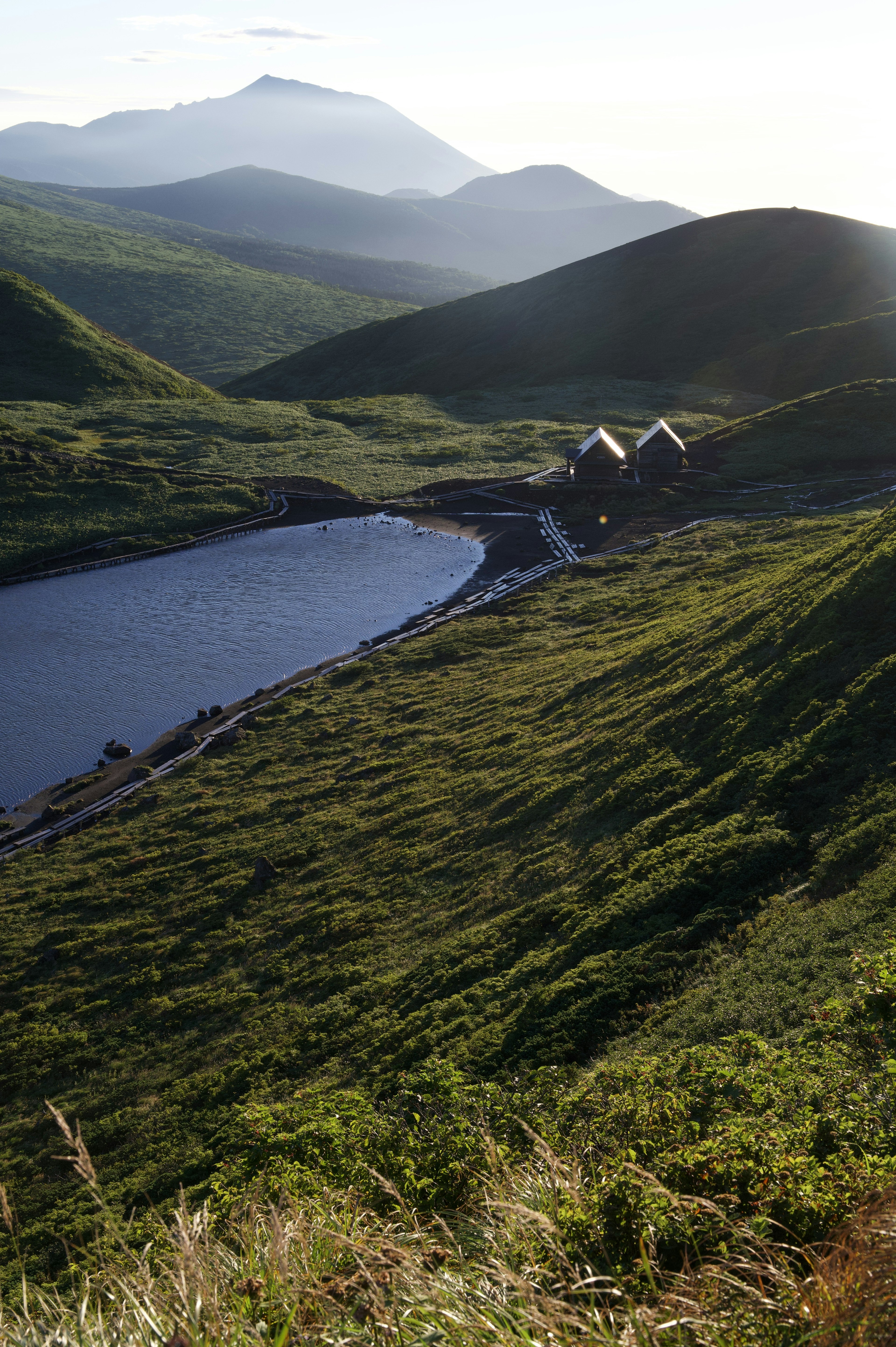 Vue pittoresque de collines vertes et d'un lac avec de petites cabanes