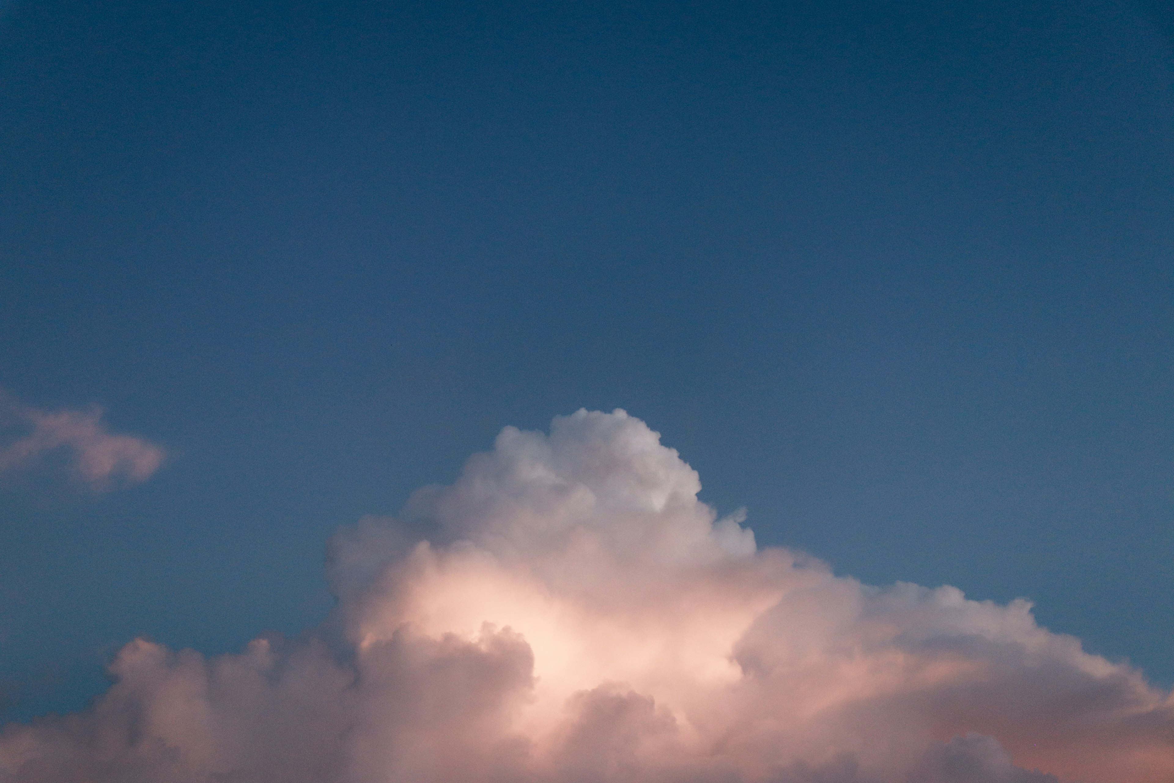 Soft clouds illuminated by sunset against a blue sky