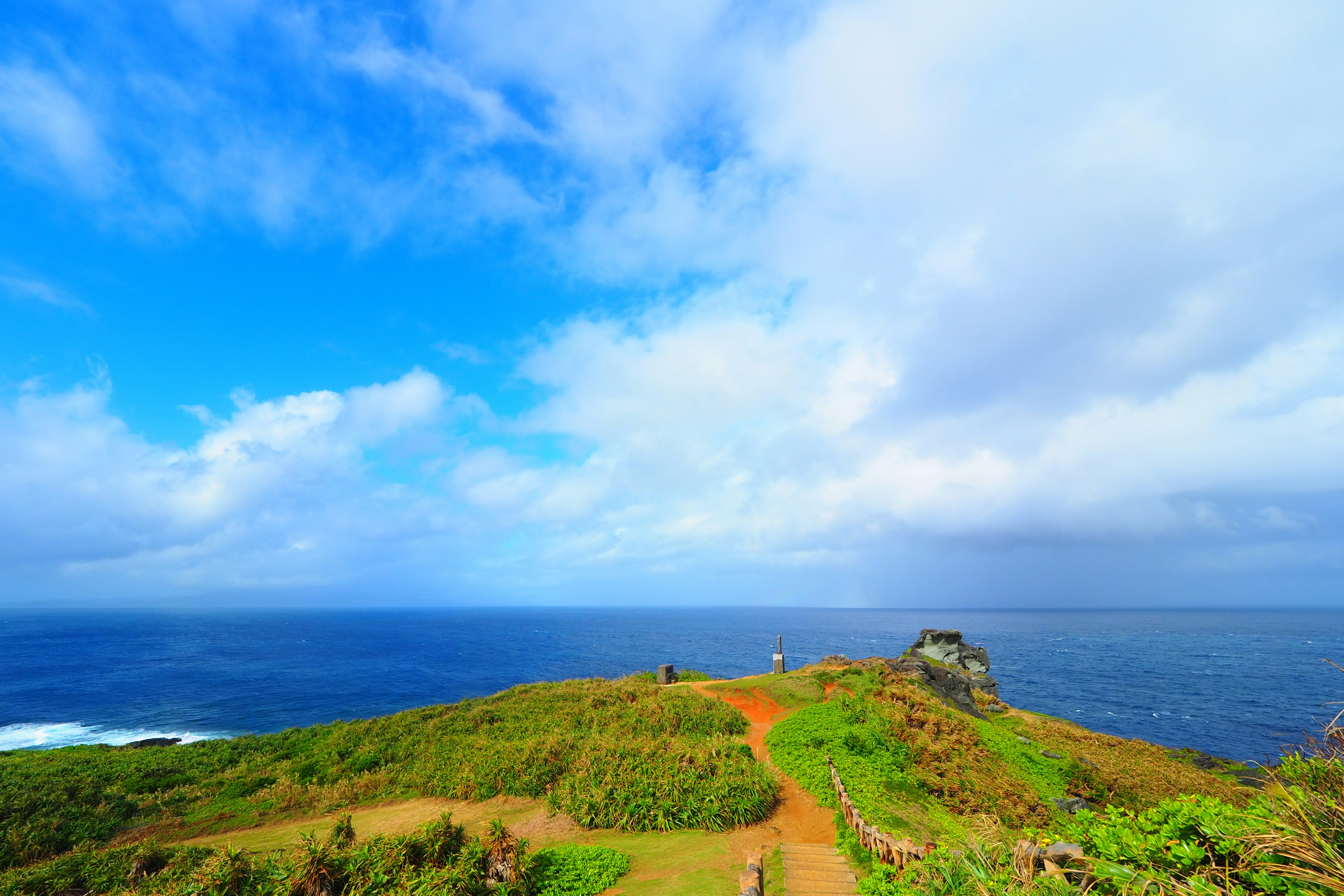 Pemandangan bukit hijau dengan langit biru dan lautan