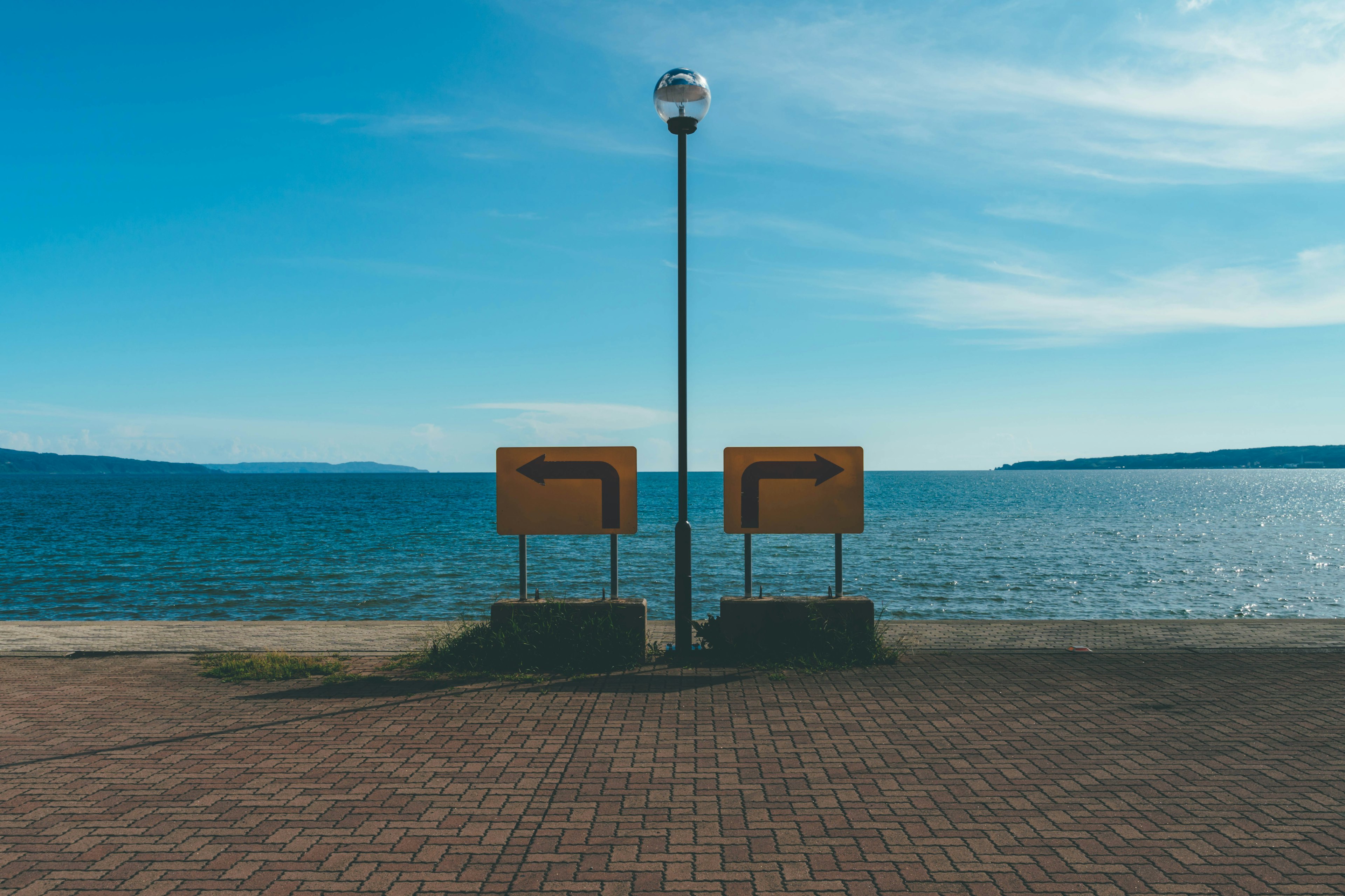 Dos bancos y un farol frente al mar bajo un cielo azul