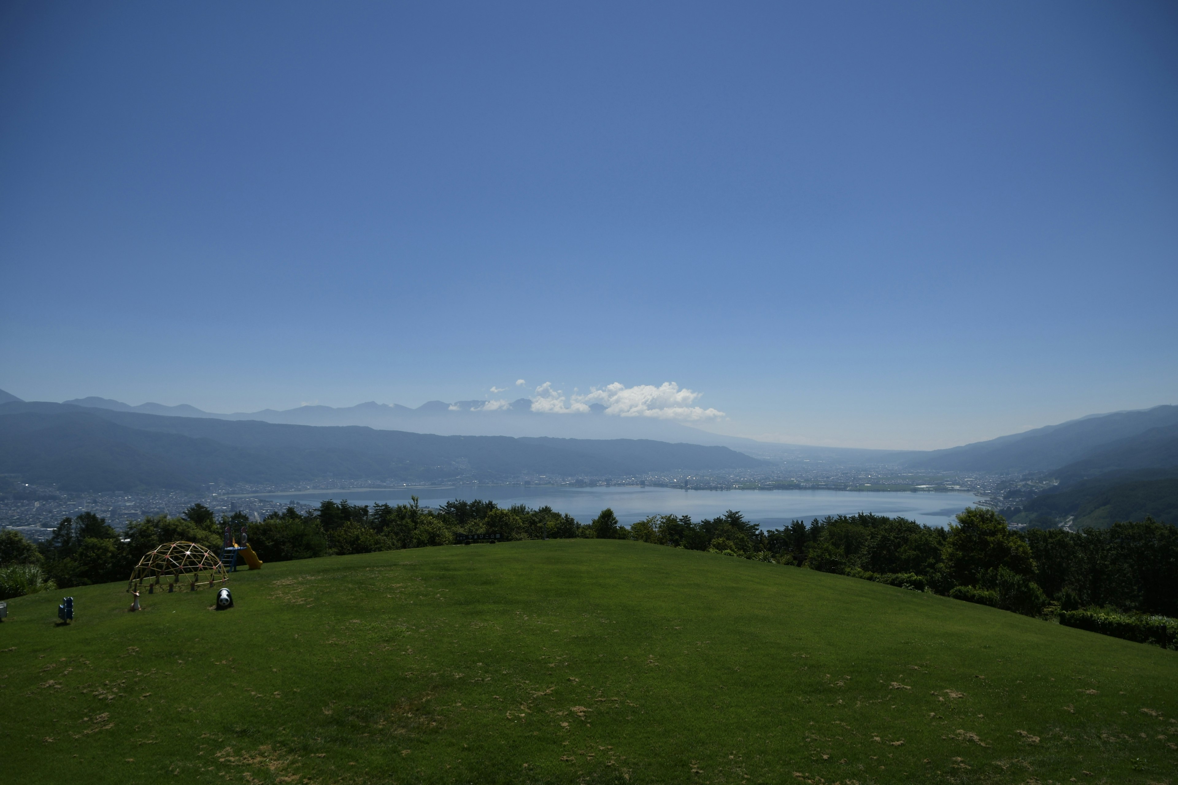 青い空と緑の草原が広がる風景 湖と山々が見える