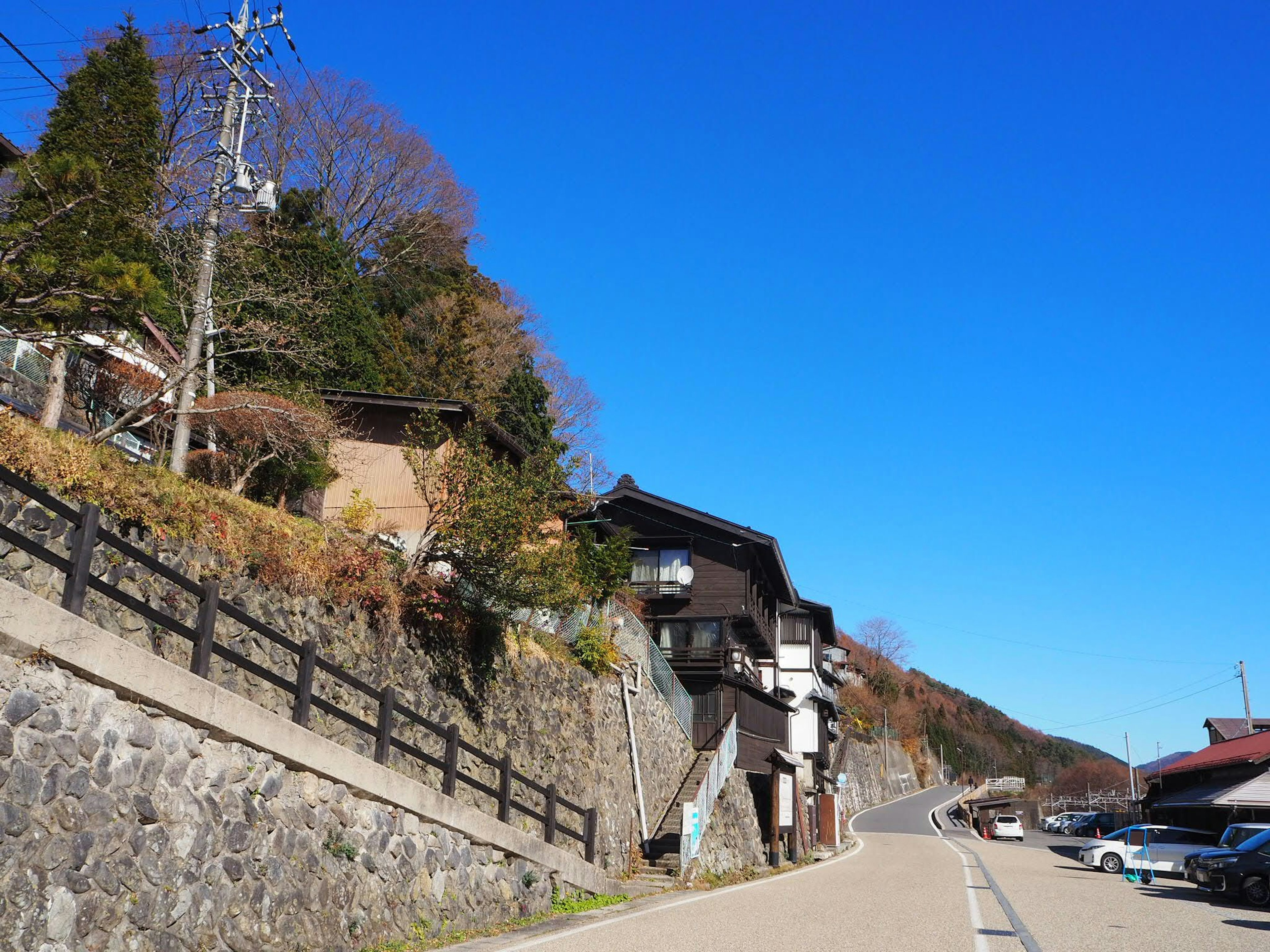 Case giapponesi tradizionali lungo una strada in collina sotto un cielo blu chiaro