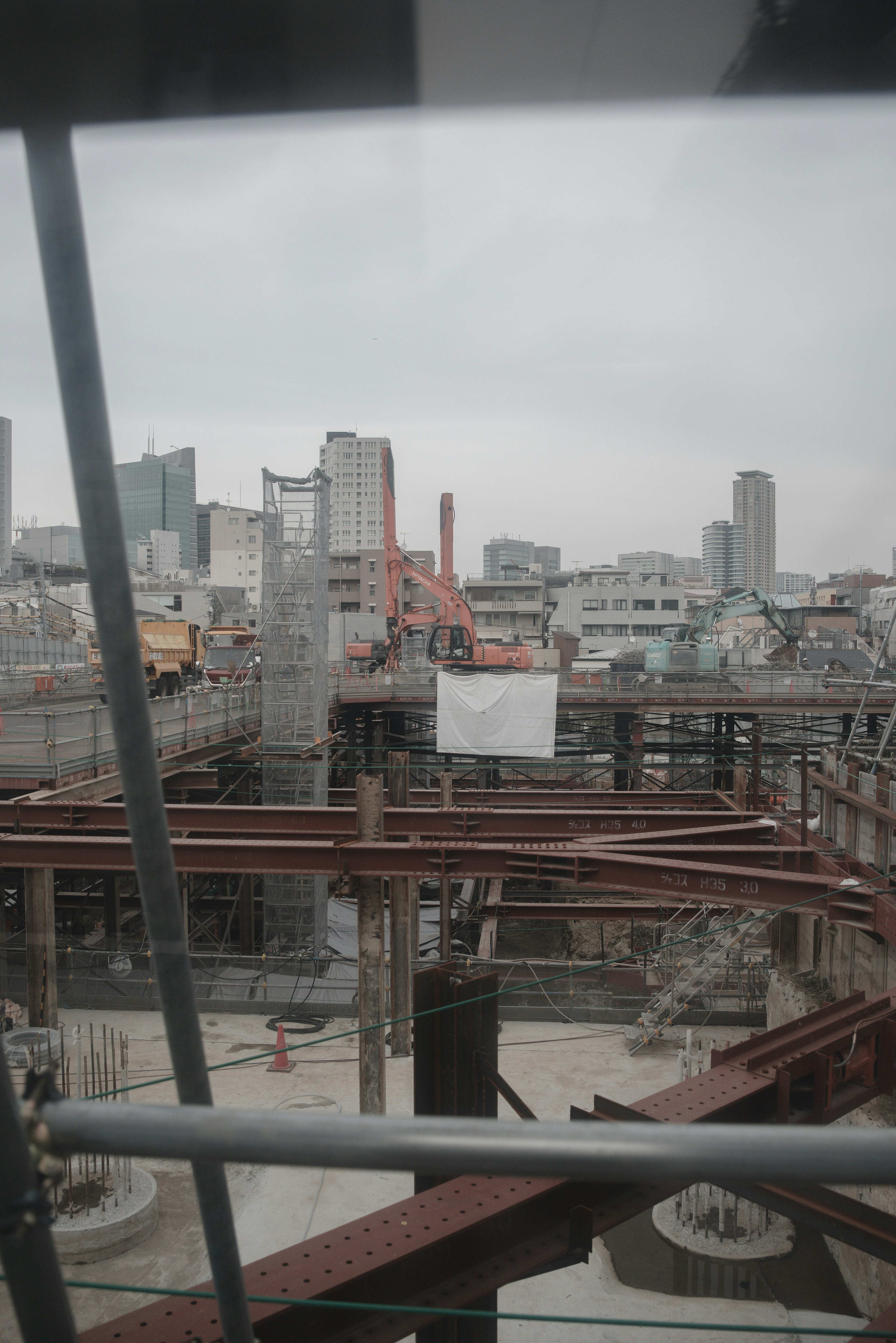 Construction site featuring steel structures and a crane in an urban setting