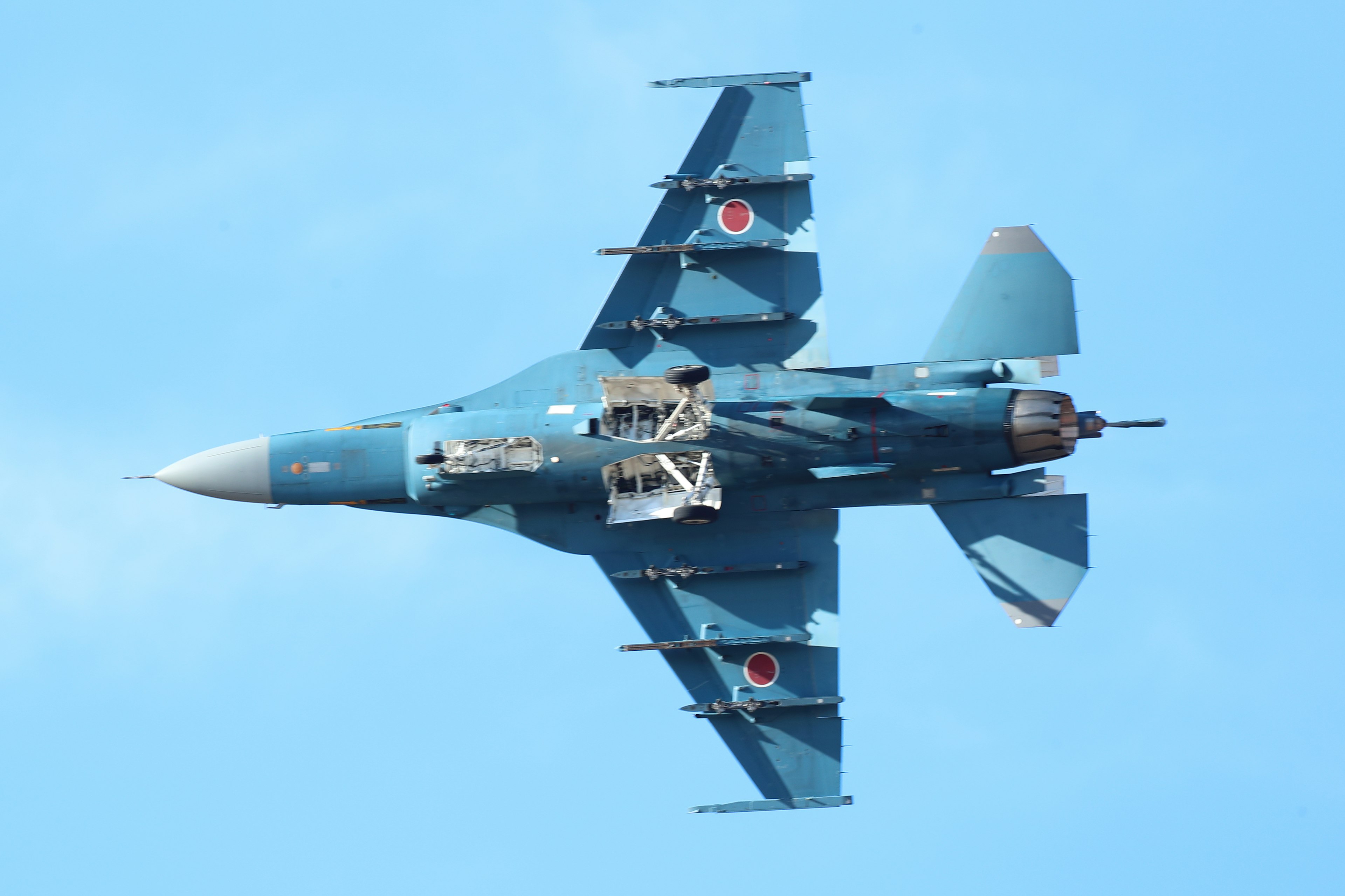 Blue fighter jet flying with Japanese flag markings