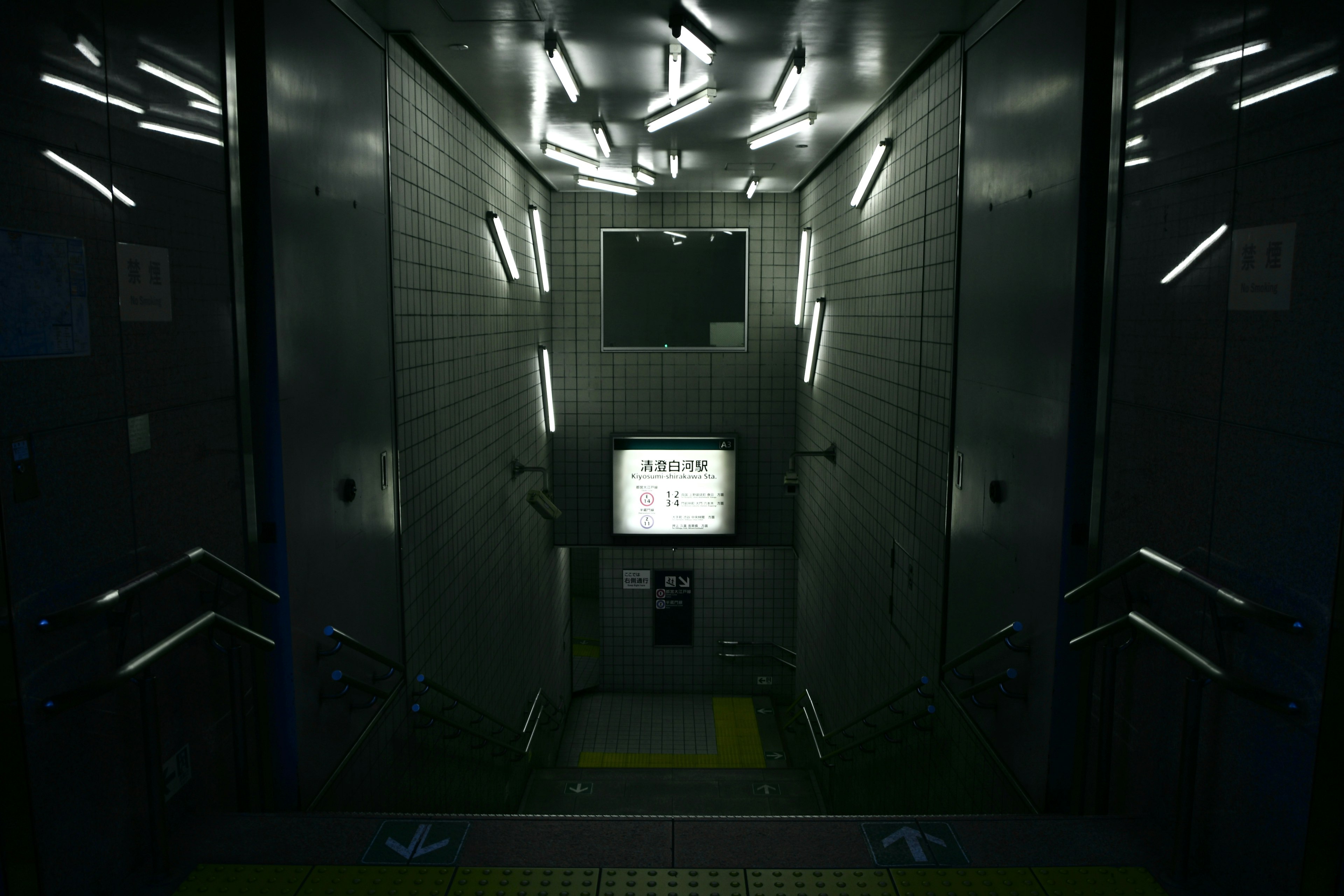 Interior of a dark elevator with glowing fluorescent lights and a central display