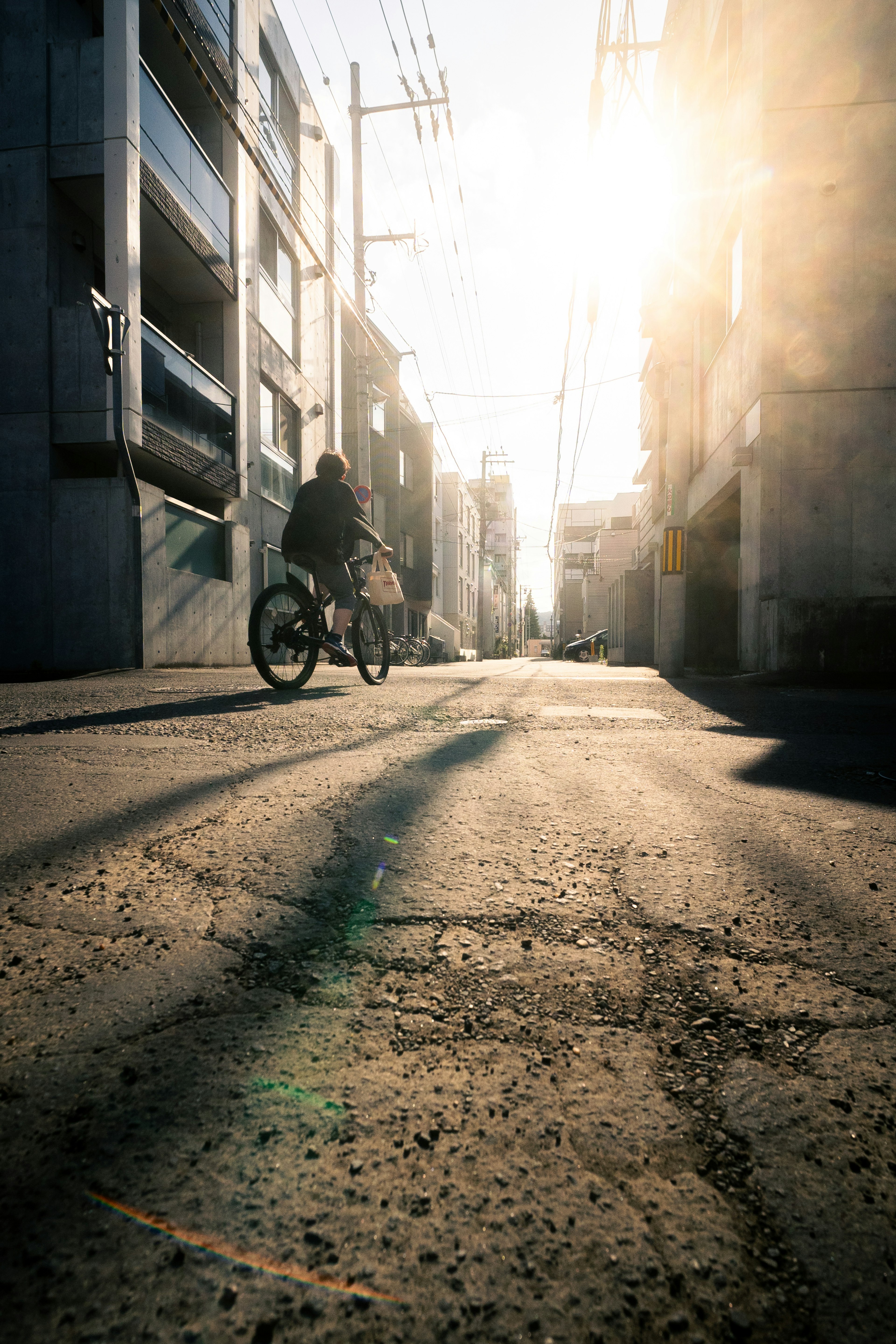 A person riding a bicycle in a narrow alley with the sunset in the background