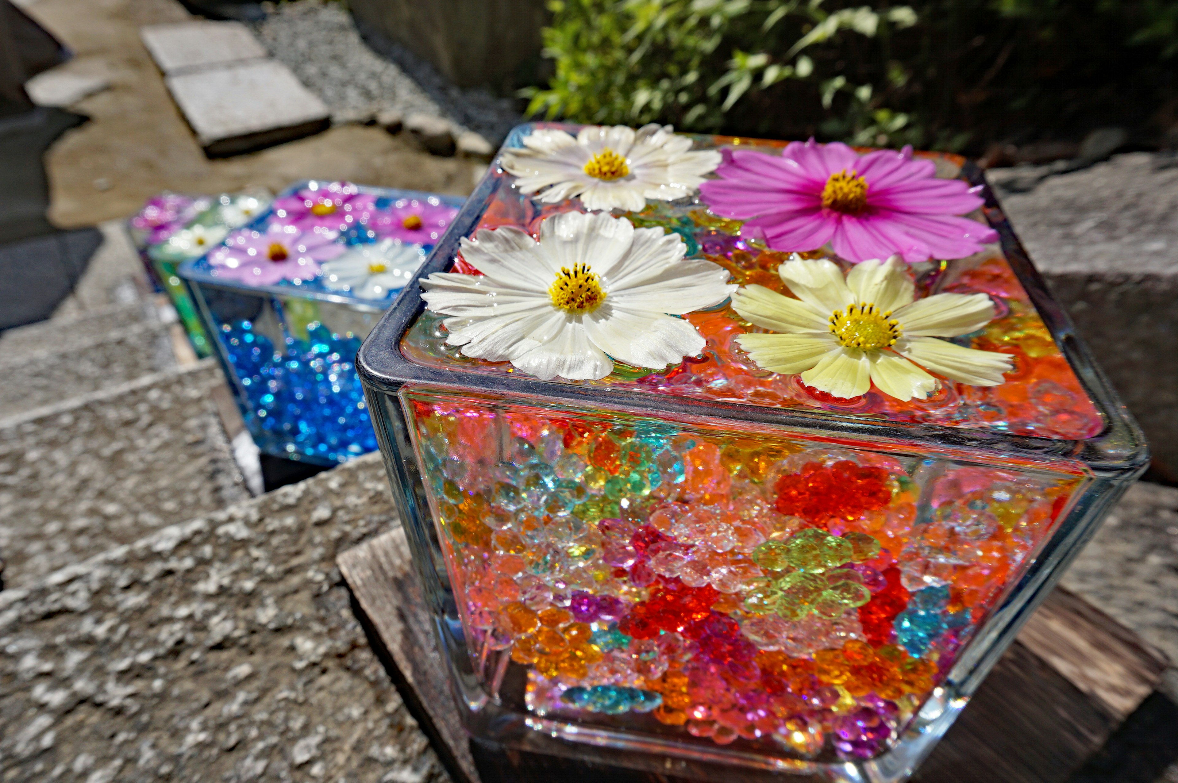 Colorful jelly-like beads and flowers in a transparent cube-shaped art piece