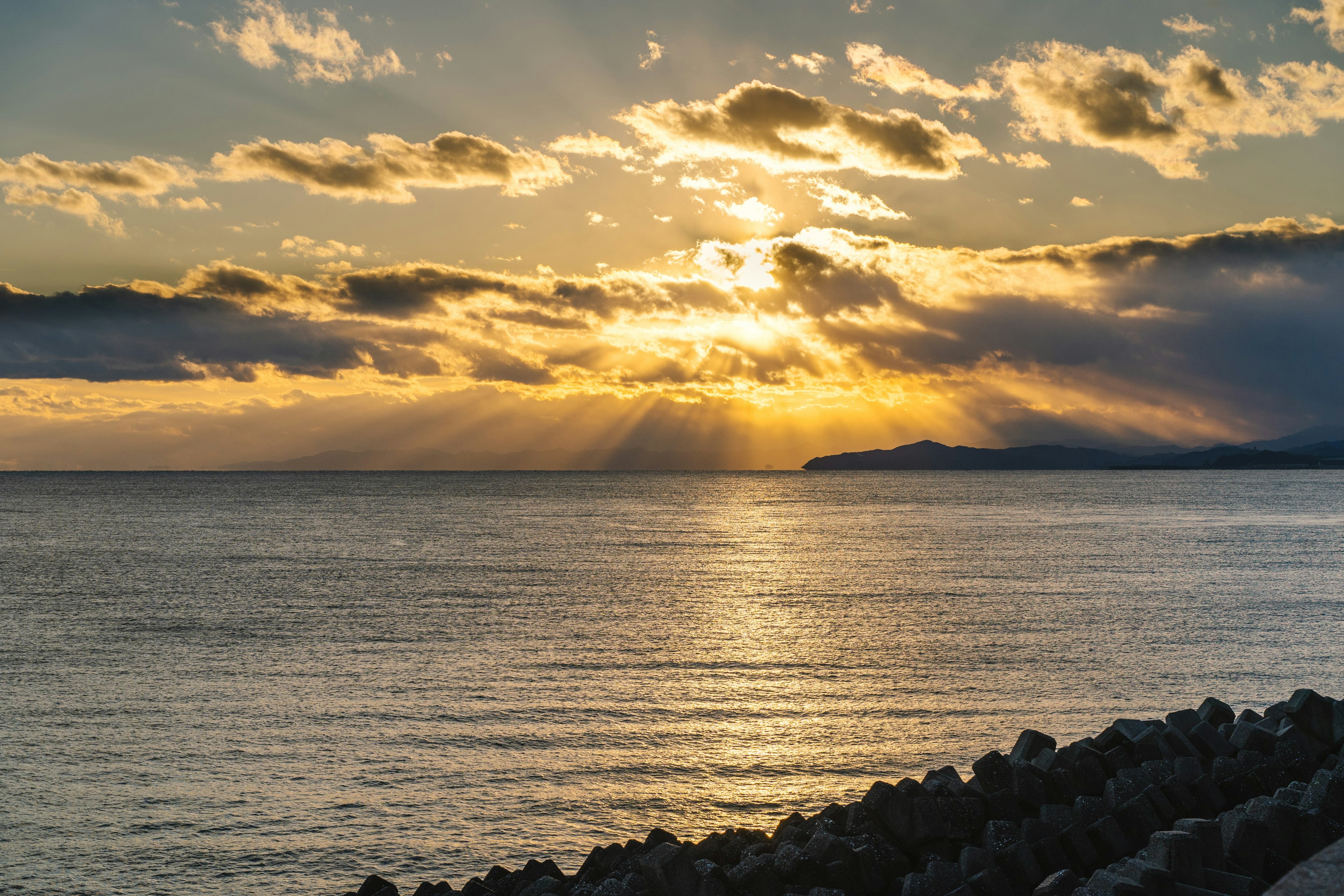 美しい夕日が海に沈む様子と雲の間からの光のビーム