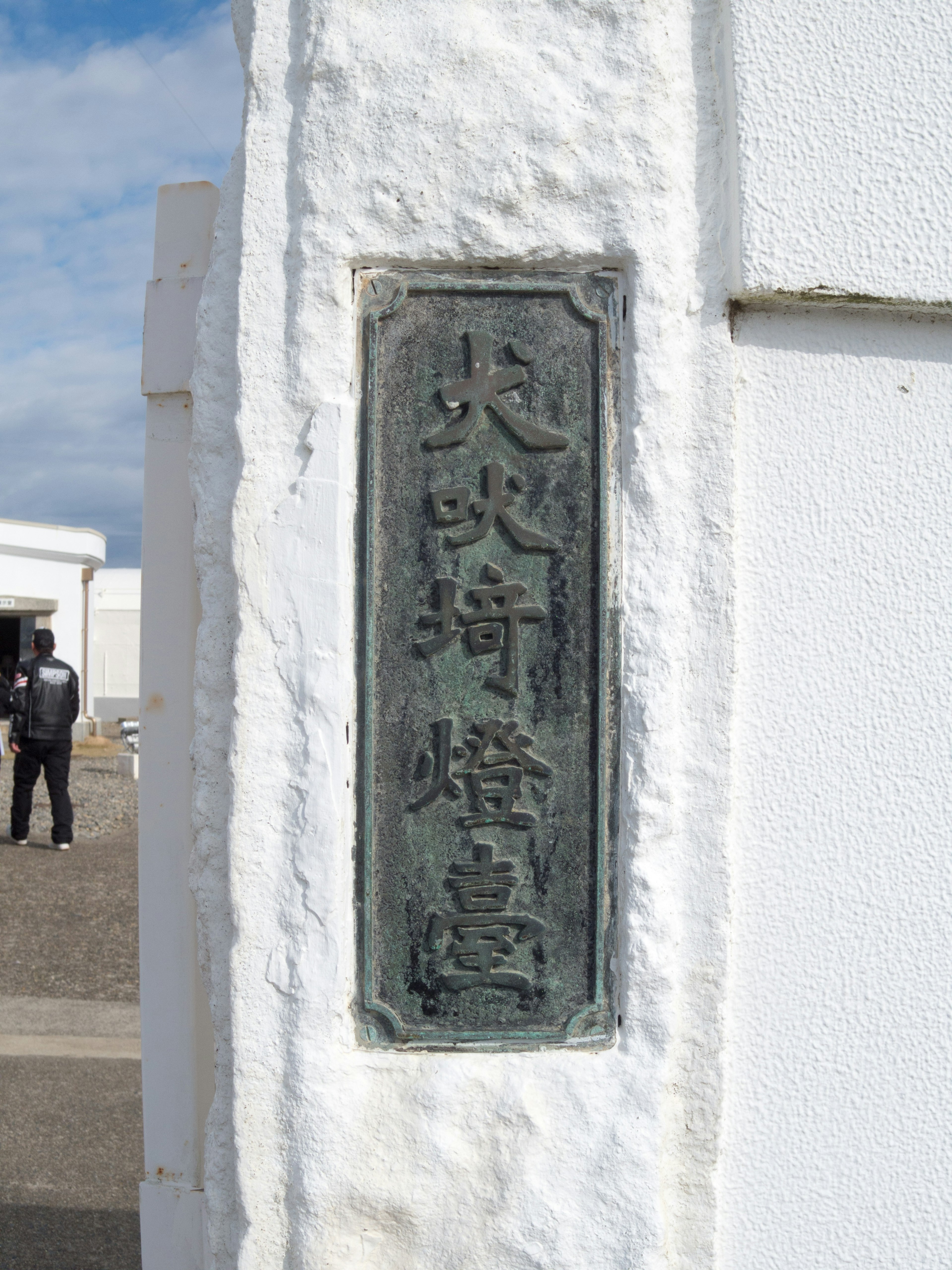 Placa de bronce montada en una pared blanca con caracteres grabados