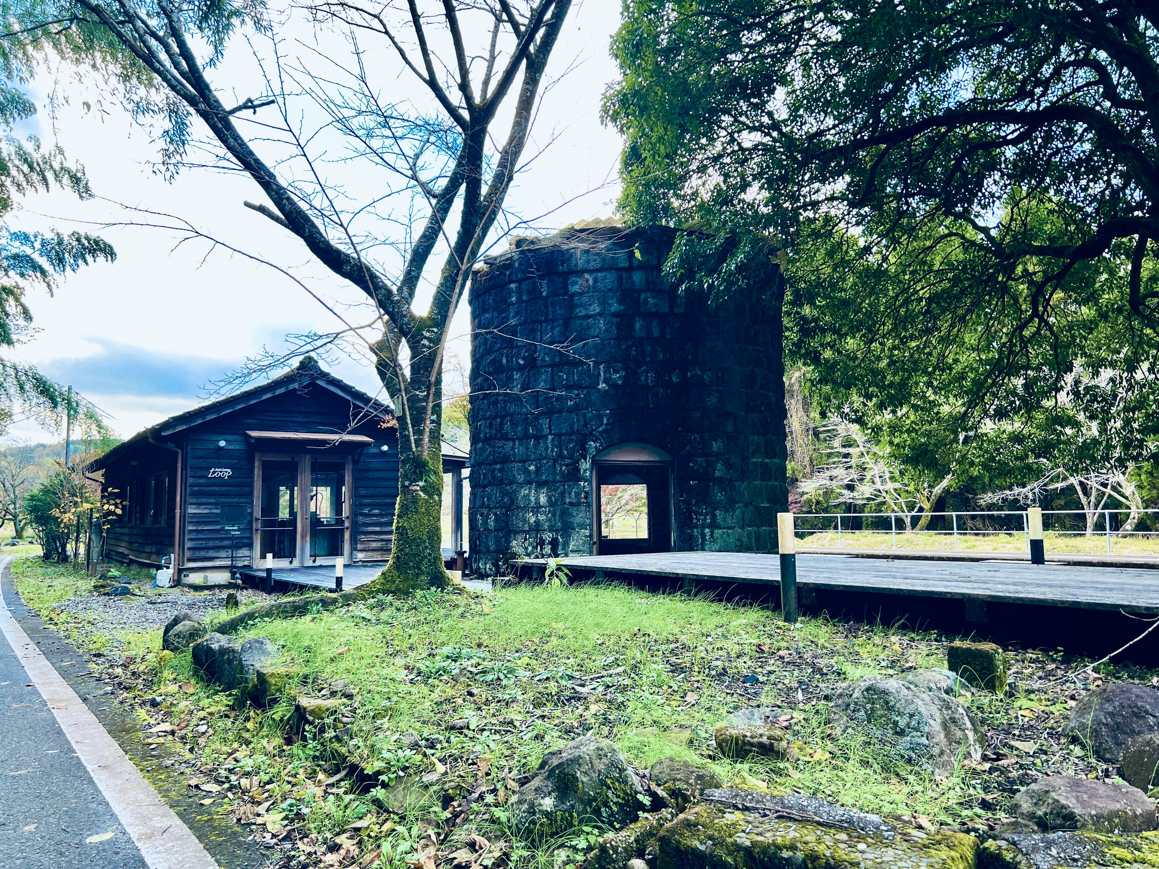 古い小屋と黒い建物が並ぶ風景 緑豊かな草と木々に囲まれた場所