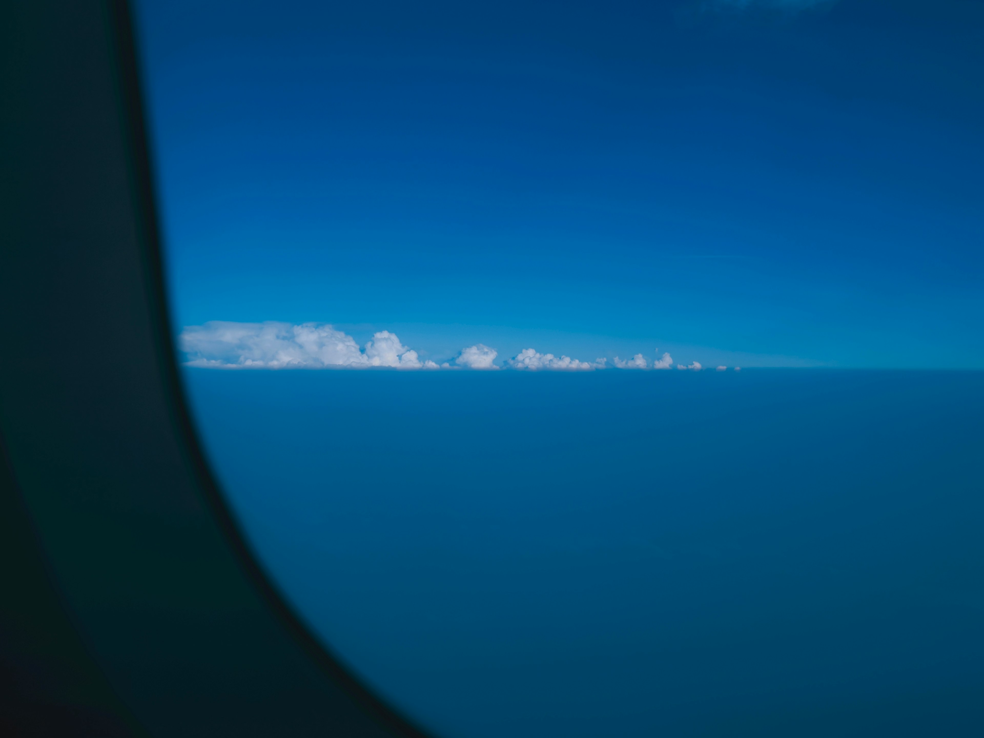 飛行機の窓から見える青空と雲の景色