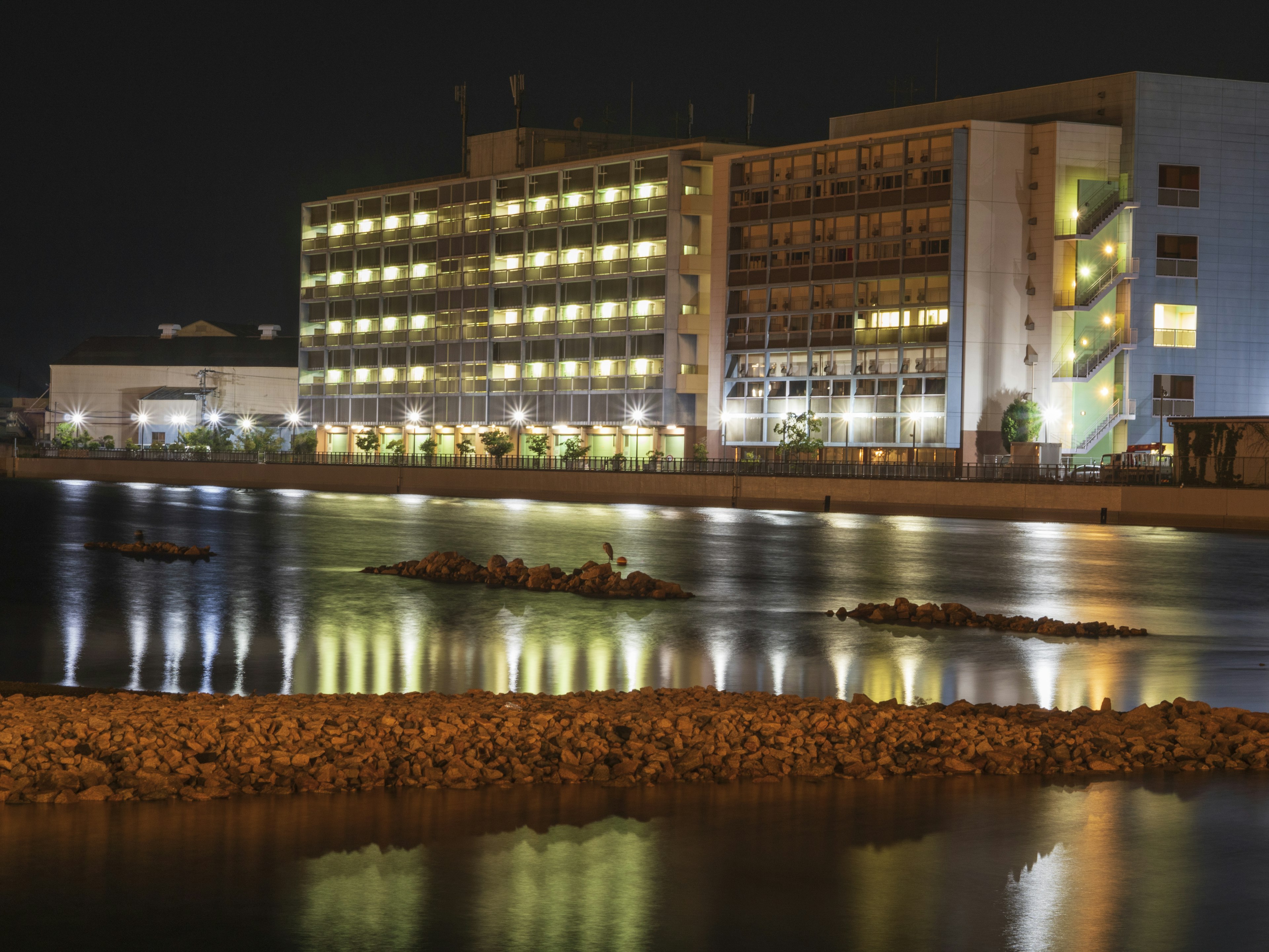 夜の海の近くにある明るい建物と穏やかな水面