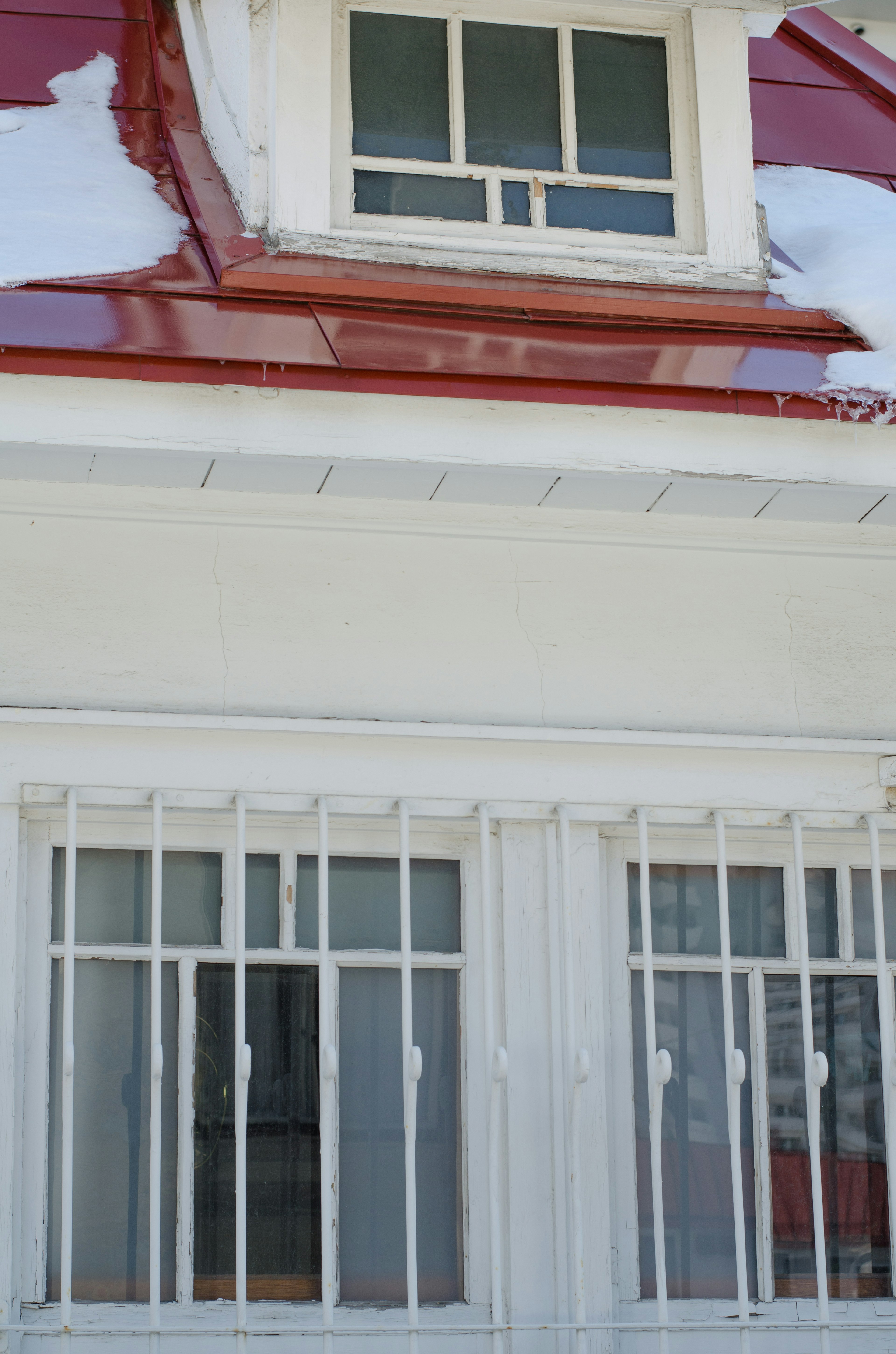 Maison blanche avec toit rouge et neige dessus