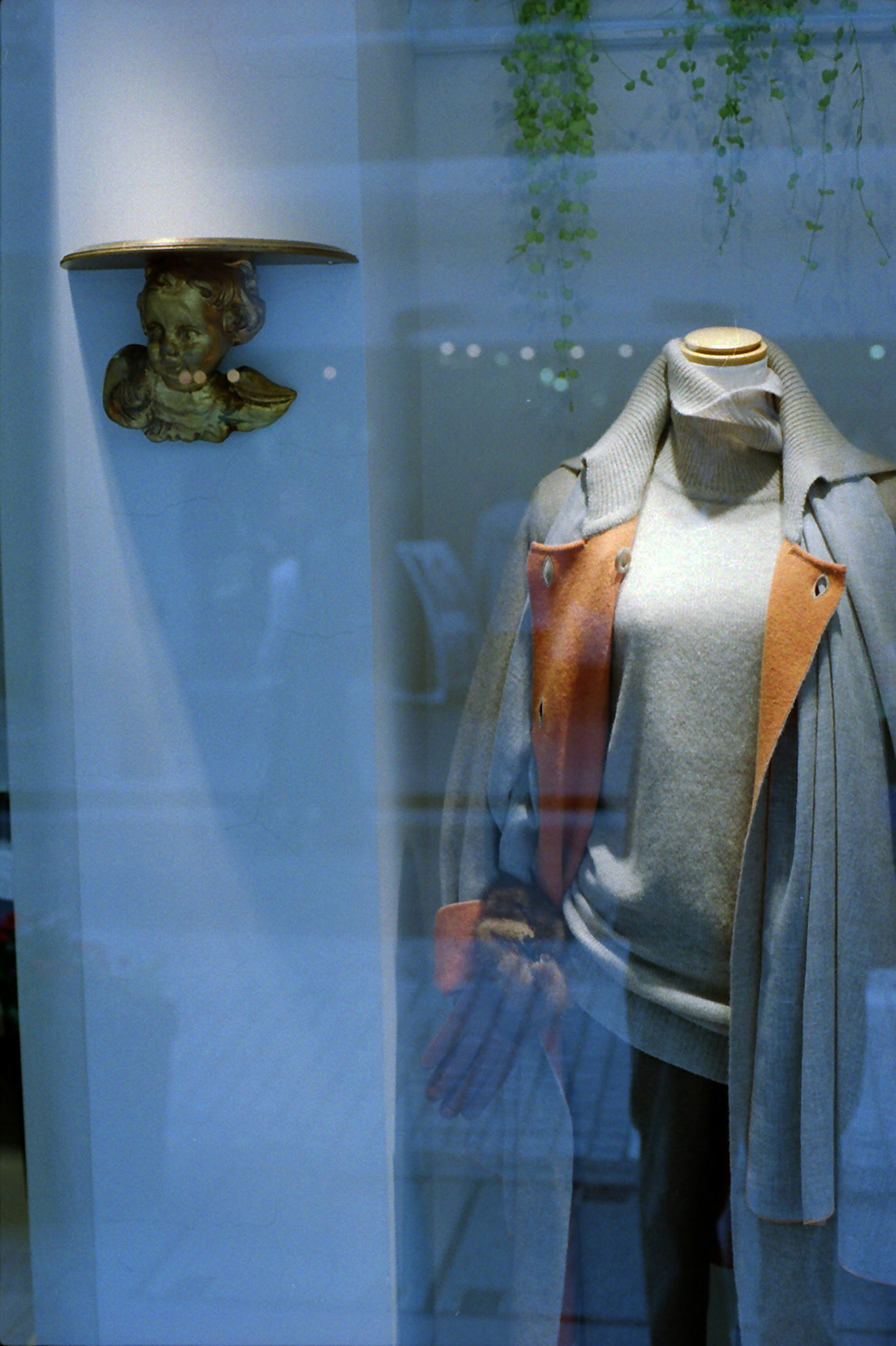 Display window featuring a mannequin dressed in a sweater and coat