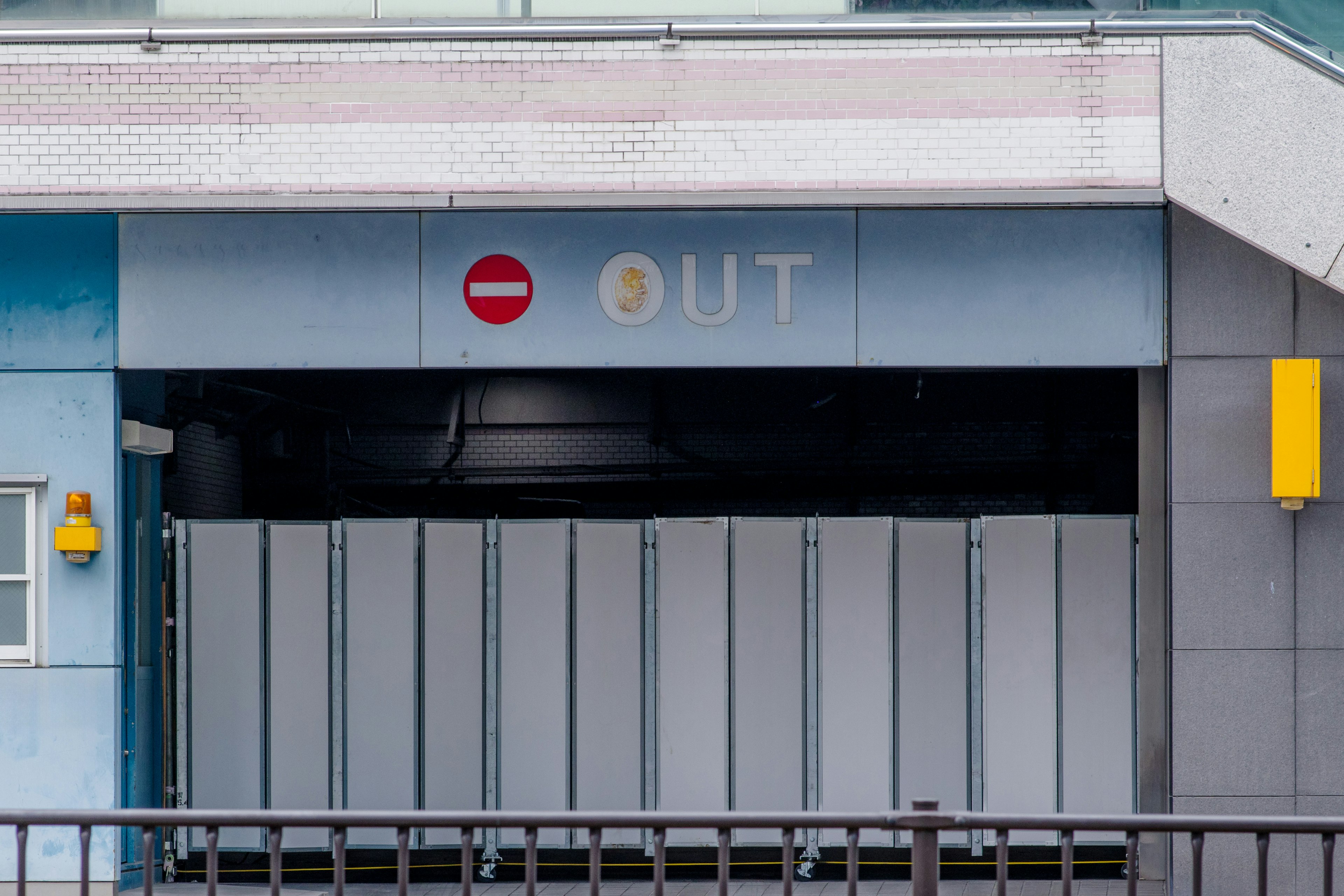 Entrada de un edificio azul con un letrero 'OUT' y un símbolo de no entrada rojo